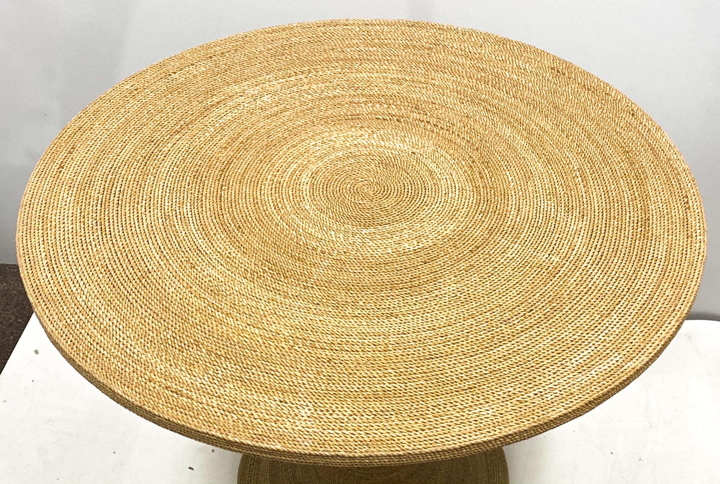 This is a modern tulip style woven seagrass table that dates to the 1970s. It is in very good condition and is unmarked. The seagrass is a series of concentric circles. Glass recommended for hard use.