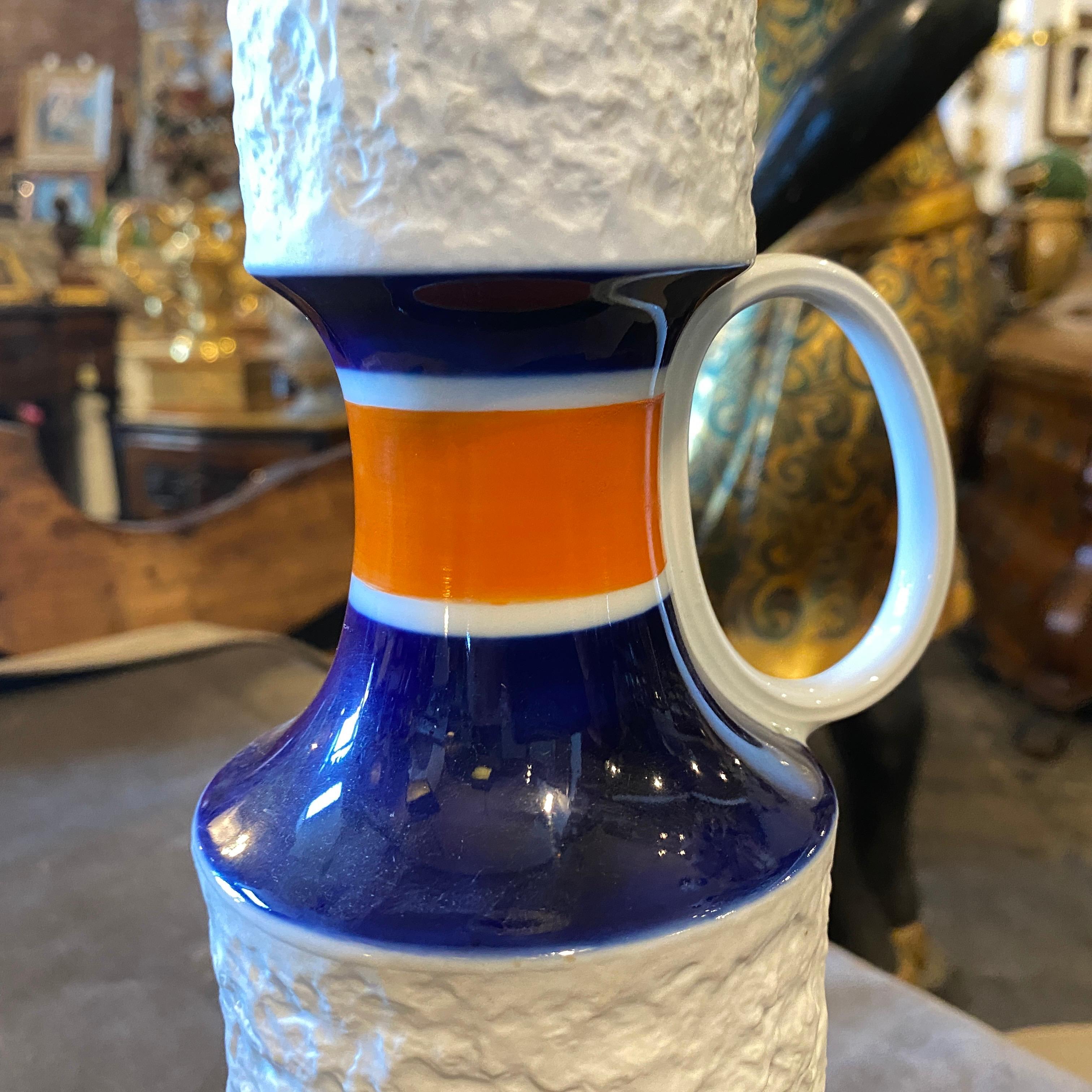 It's a stylish vase made in Germany by K.P.M. White, orange and blue cobalt ceramic it's perfect conditions. This jug by K.P.M. is a striking and contemporary piece that exemplifies the design trends of the 1970s Modernist movement. K.P.M.  is a