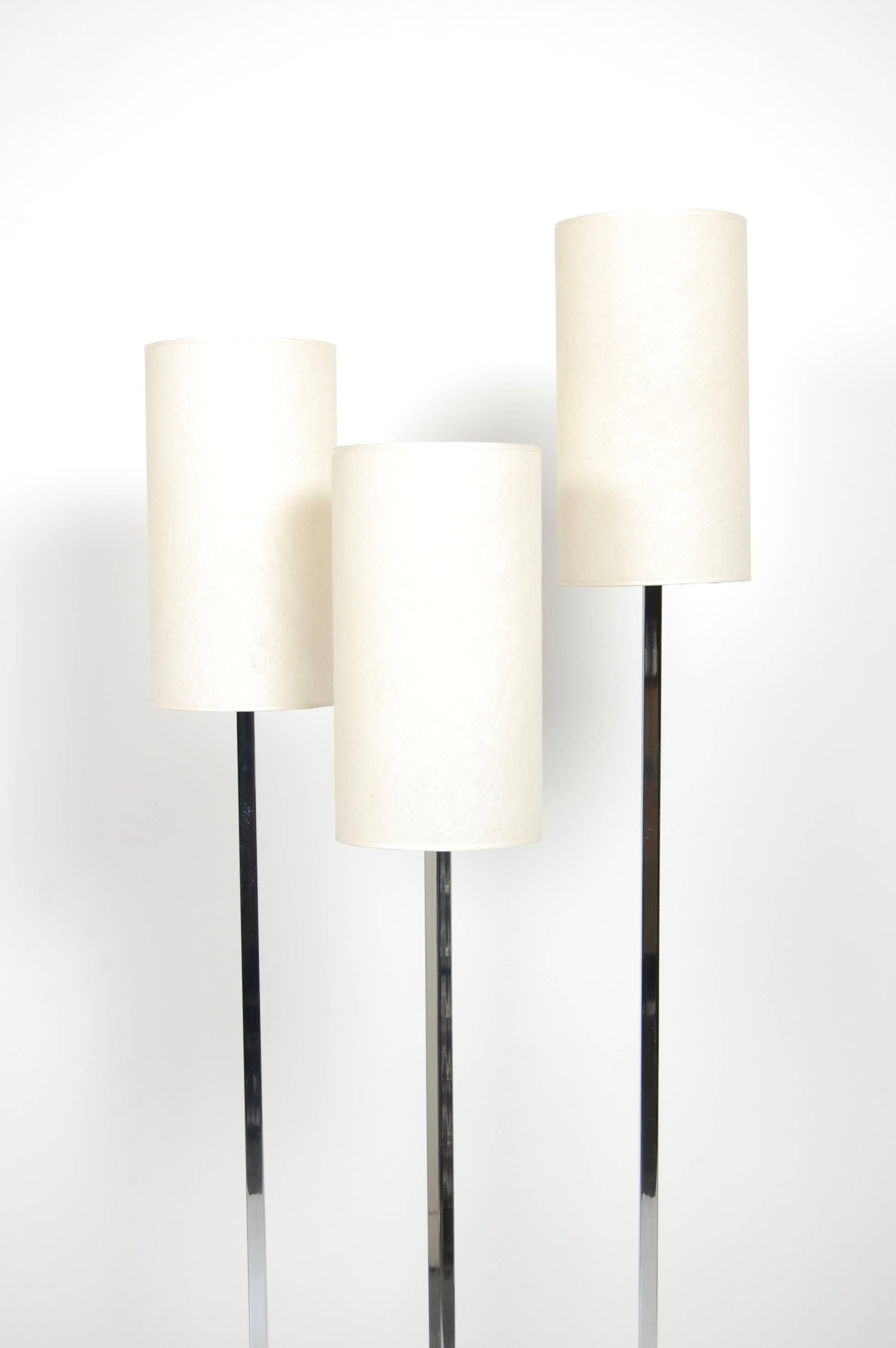 1970s three shade floor lamp with asymmetrical black cast iron base. The original off white shades are cylindrical and in excellent vintage condition. The upright light stems are chromed and the light is operated via a foot switch.