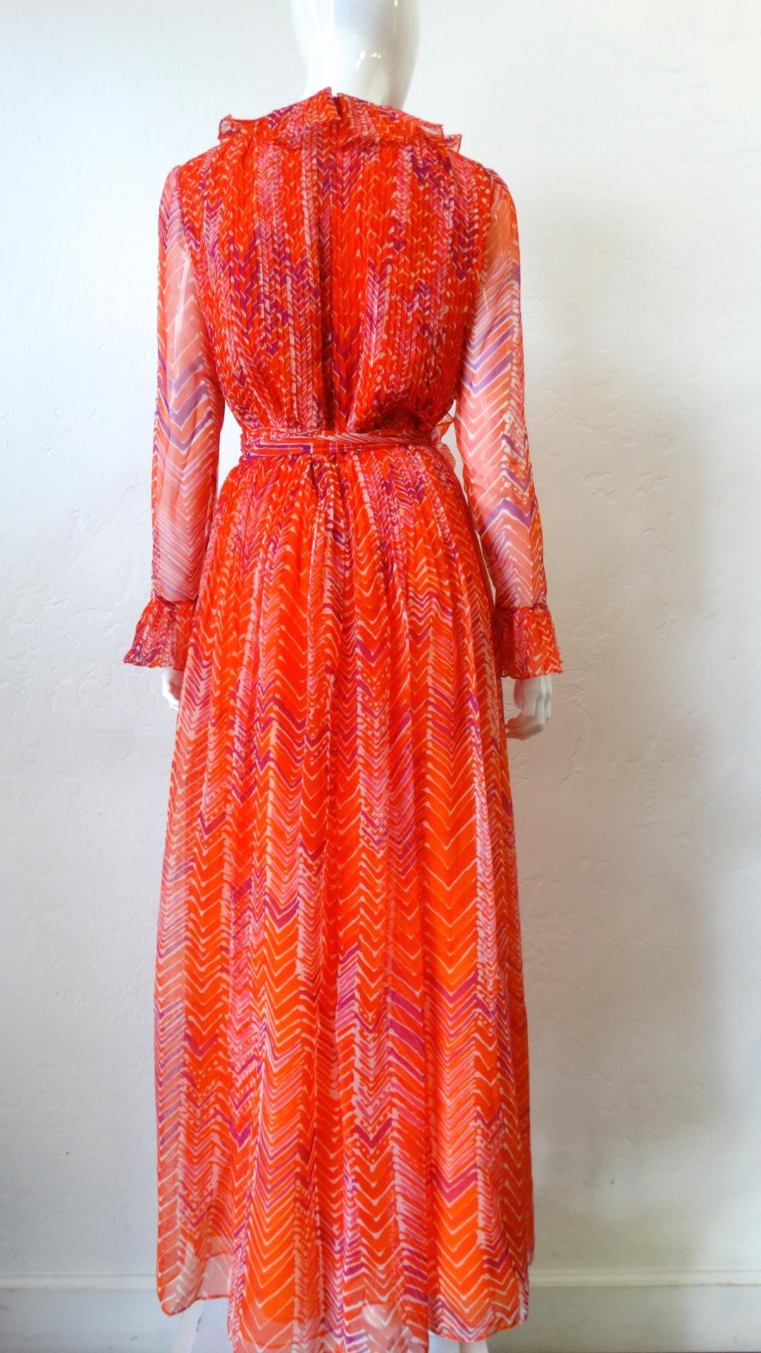 The Perfect Dress For Every Occassion Is Waiting! Circa 1970s, this Mollie Parnis sheer maxi dress features a vibrant asymmetrical abstract motif. Includes sheer long sleeves with ruffle cuffs, a pleated neck ruffle and a removable waist tie. Bodice