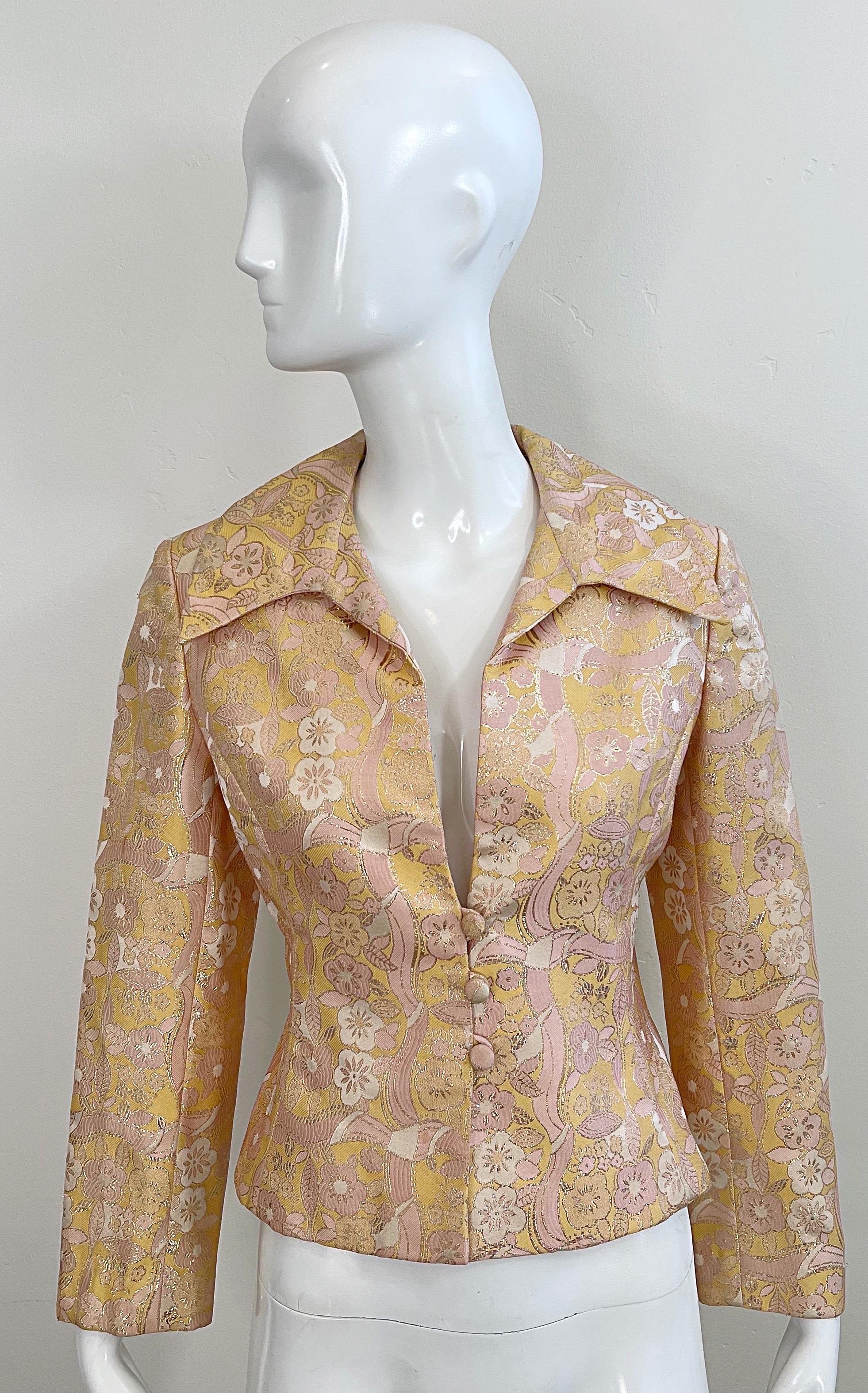 Chic early 1970s MOLLIE PARNIS peach, pink, ivory and gold silk brocade jacket or blouse ! Exaggerated lapels with three fabric covered buttons down the front. Metallic flower print throughout. Perfect layered over a blouse or alone.
In great