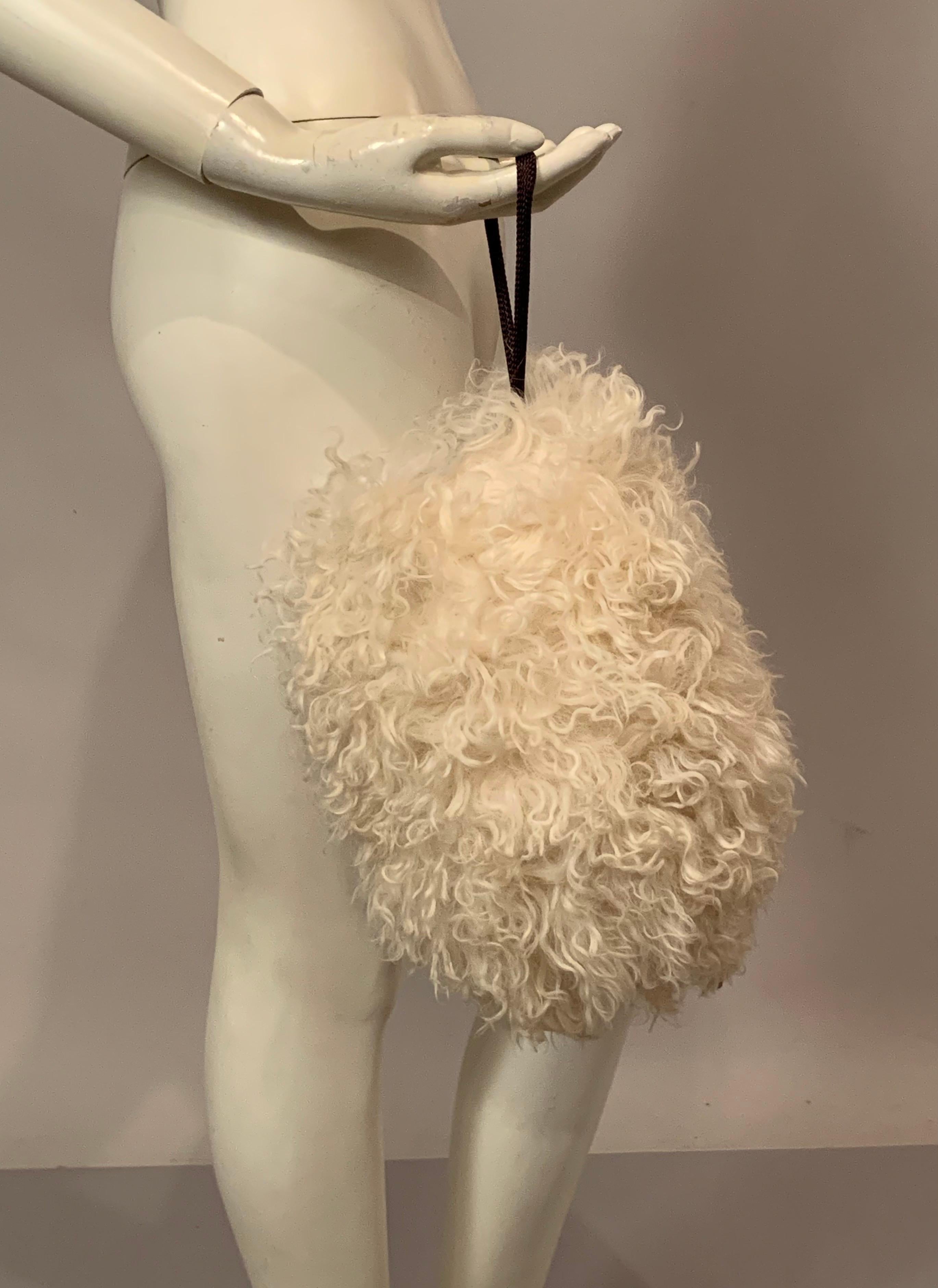 Add a little glamour to these cold weather days! This lovely Mongolian curly lamb muff is just the thing to keep your hands warm in style. The muff is lined with chocolate brown satin and there is a zippered pocket inside as well as a wrist strap.