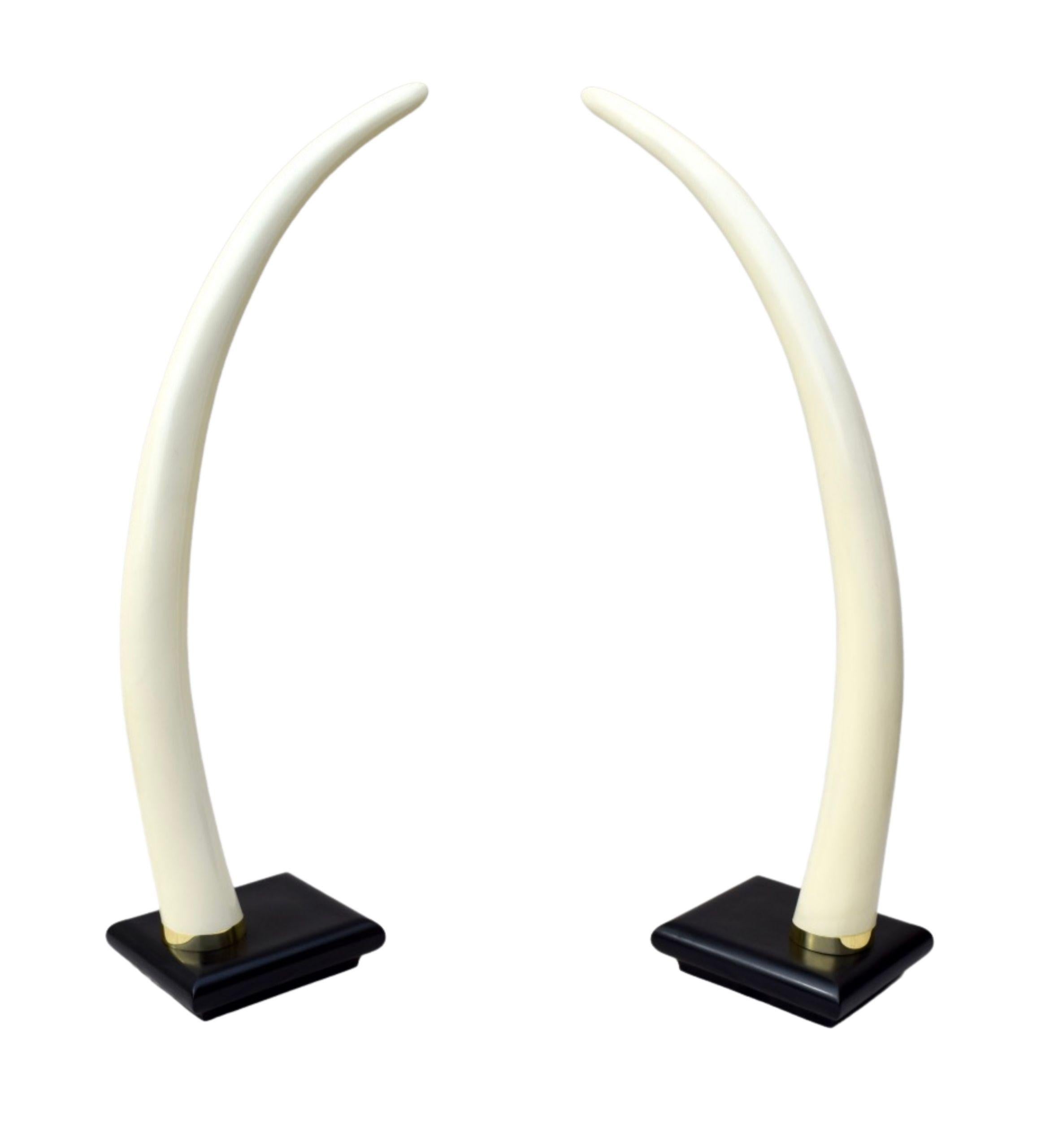 Impressive pair of Mid-Century Modern faux tusks of arched monumental form on lacquered wood bases, enhanced with brass collar mounts; circa 1970s. Base dimensions: 18