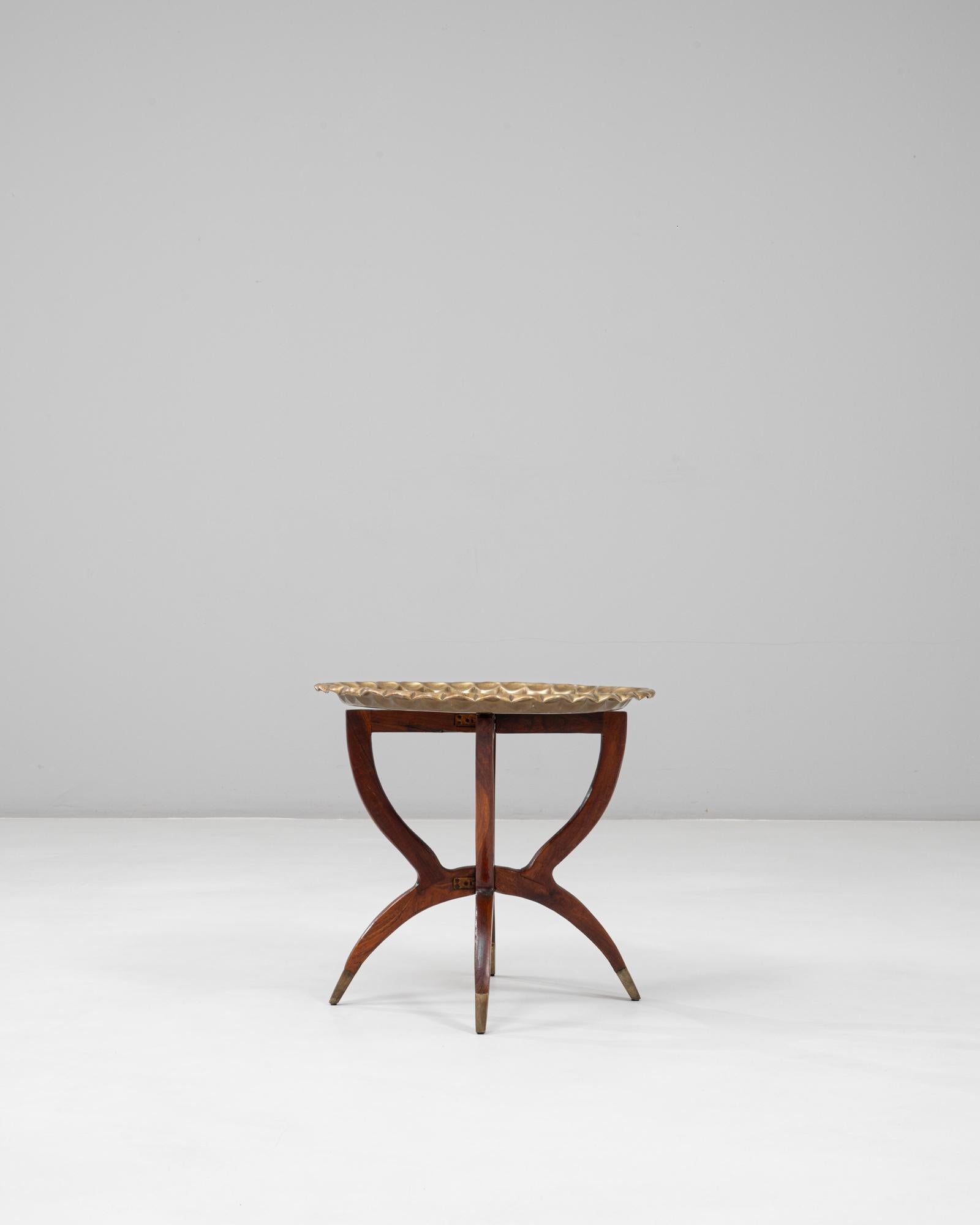 This 1970s Moroccan Mid-Century coffee table combines sculptural form with artisanal detail. The solid walnut base features elegantly curved spider legs with brass-capped feet, creating a refined sense of balance and movement. The circular bronze