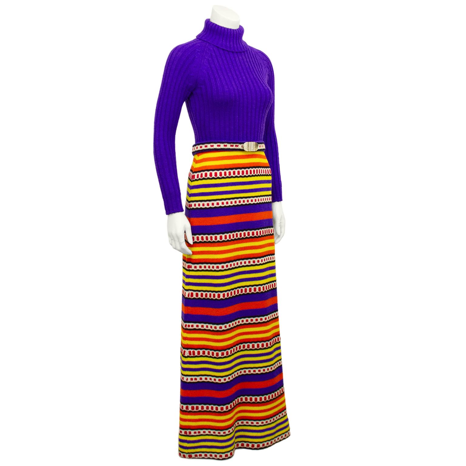 Vibrant and fun poly /wool knit maxi dress from the 1970s. Made in Canada by Marni Knits. Top is ribbed knit purple turtleneck. Bottom is a slight a-line maxi shape with yellow, orange, purple, red, black and white horizontal stripes. Optional