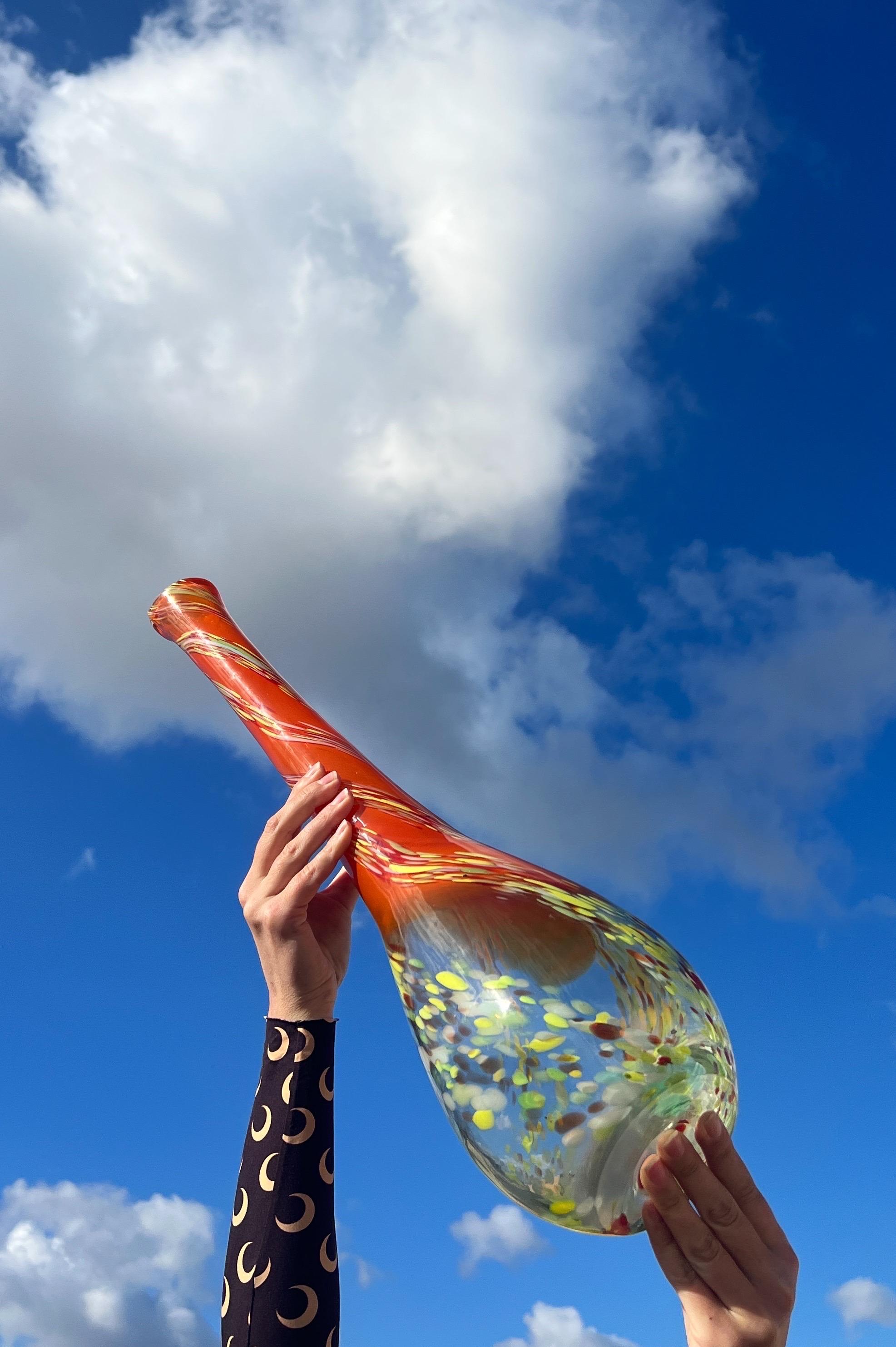 Voici un superbe vase en verre de Murano tout droit sorti des vibrantes années 1970 ! Cette pièce exquise présente une étonnante fusion de couleurs. 

À la base, un verre transparent avec de vifs tourbillons de 