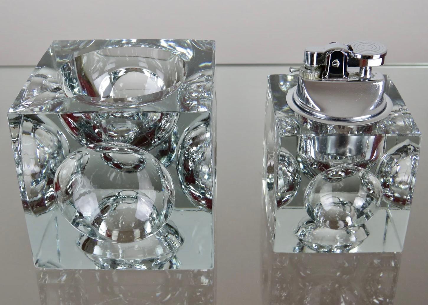 1970s heavy glass block Murano clear glass table lighter-paperweight with chrome top and matching ashtray. Cut out circular discs are cut out on each side. A dramatic accent to any modern living room decor, this Murano lighter will elevate any