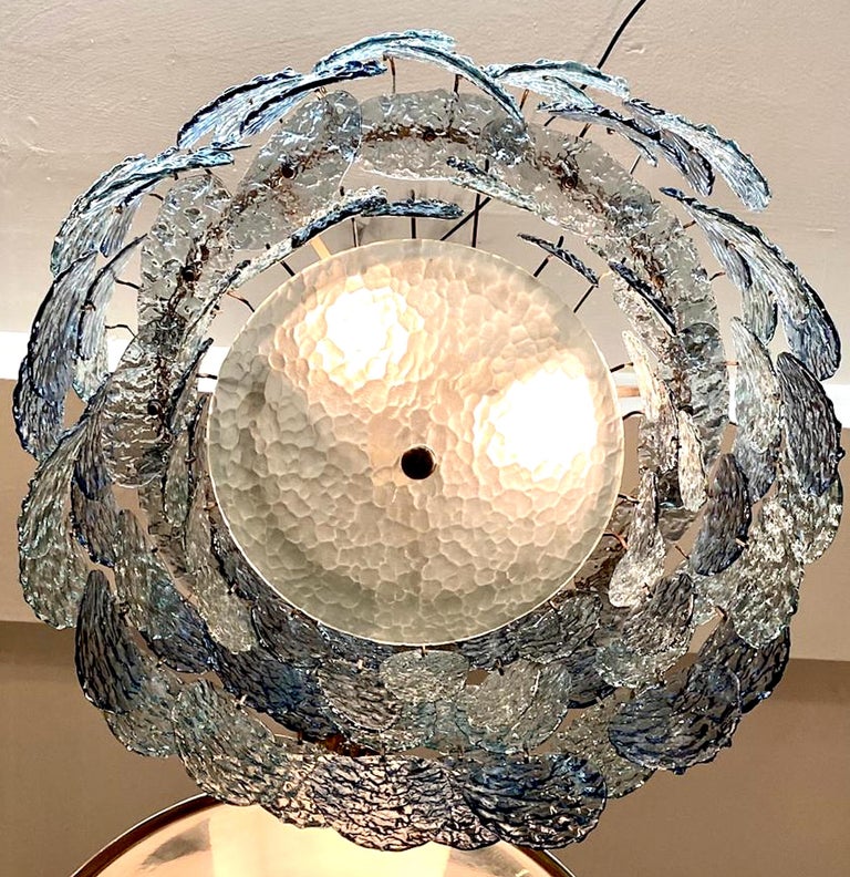 A stunning early 1970s smokey light and dark blue glass disk chandelier made in Murano, Italy. It is designed by well known Italian designer Gino Vistosi for his lighting company Vistosi. The chandelier features hand formed oval disks in a smokey