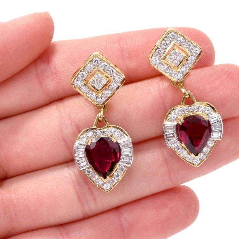 These shimmering Estate Ruby & Diamond dangle drop earrings are crafted in solid 18K yellow gold with white gold details.
These sophisticated earrings display a heart shape dangle drop centered with 2 genuine pear cut Rubies ) approx: 5.30 carats