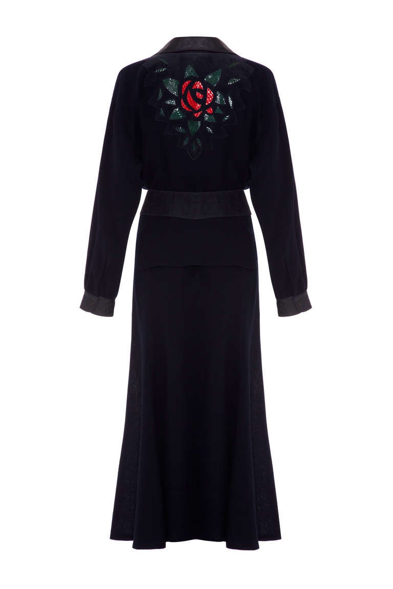 Fantastic navy lightweight wool suit from 1970’s collectable British designer Ann Buck. This suit is made up of a waisted peplum jacket and full calf length skirt with leather appliqué details in a floral design and matching belt.  The whole thing