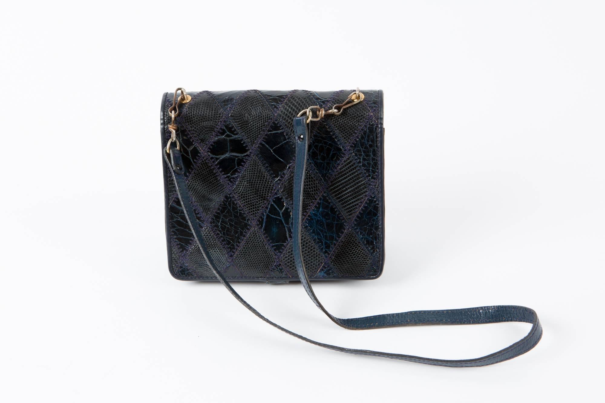 1970s navy leather patches clutch featuring  different leather & reptile leather effects, four compartments, gold tone metallic opening, a detachable 
shoulder strap (31,1in. (79cm)).
6,7 in. (17cm) X 5.9in. (15cm) X 1.18in. (3cm) 
In excellent