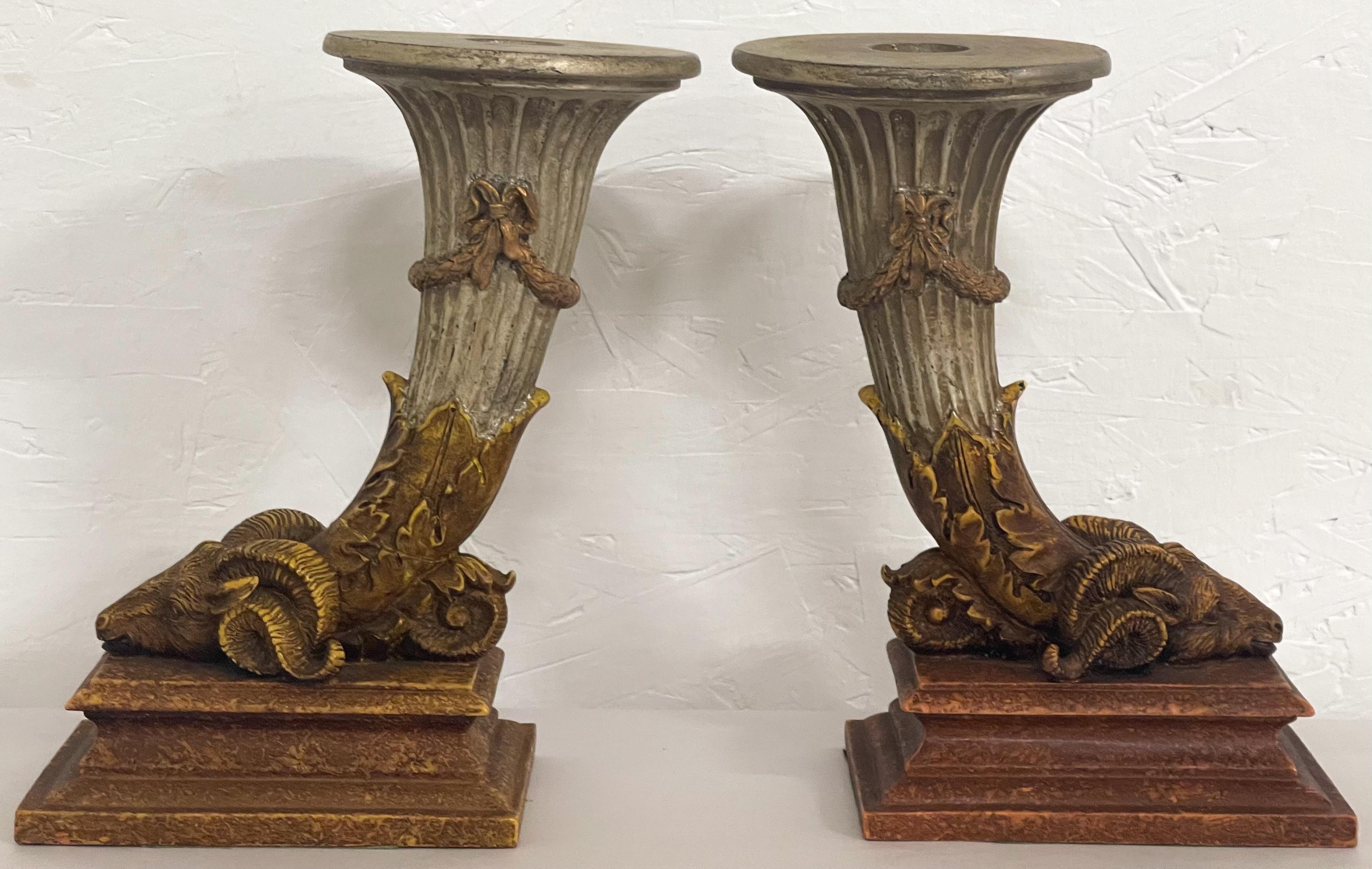 This is a good looking pair of Italian neo-classical style candlesticks. They have an elongated cornucopia that graduates downward to a detailed ram’s head. They are composition and most likely Italian.