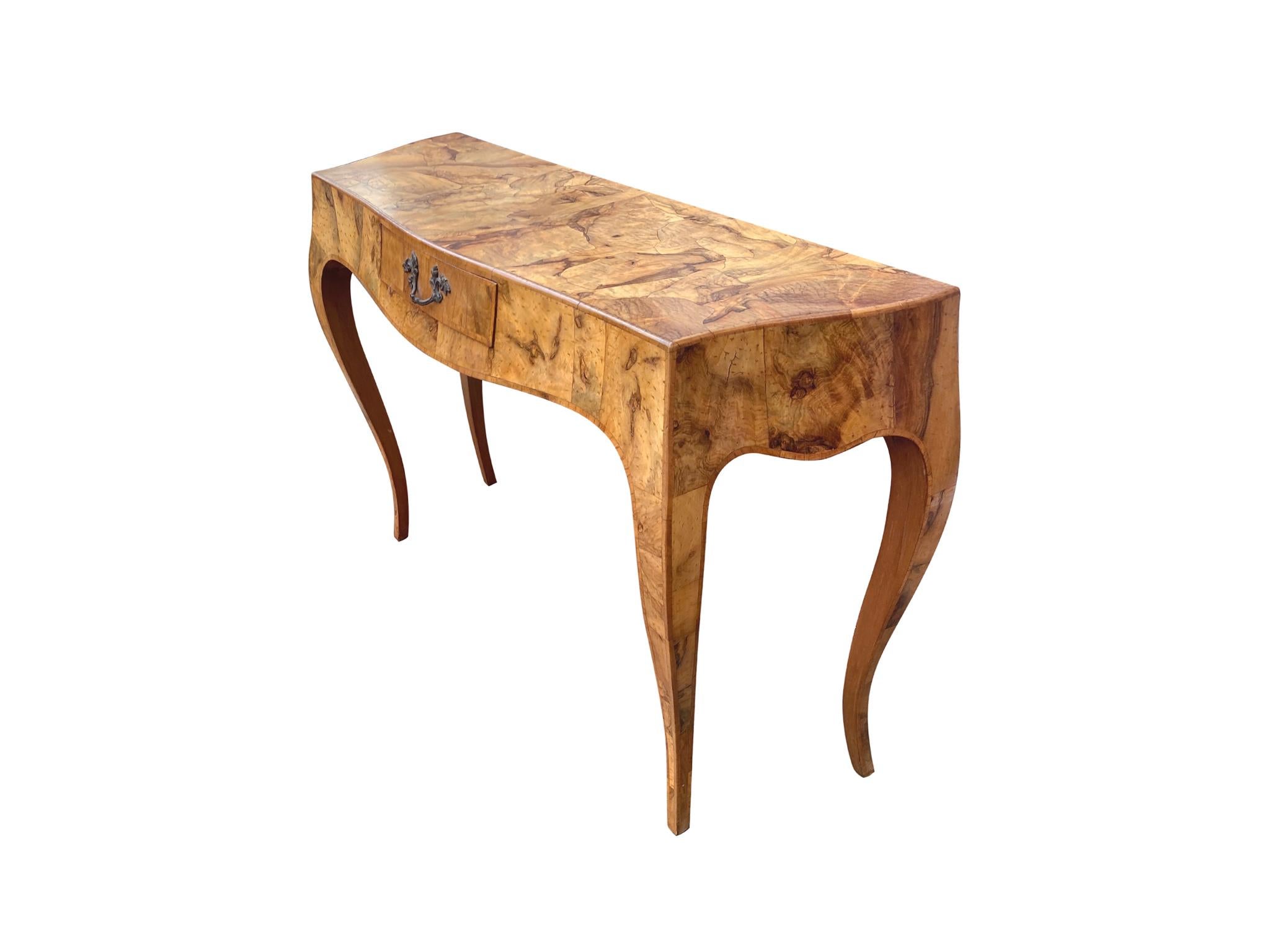 talian console table crafted in the Neoclassical style, late 20th century. Rich burl-wood veneer covers the surface creating a rich patchwork design. Other noteworthy features we love are the bowed front and curved legs. The single drawer with a