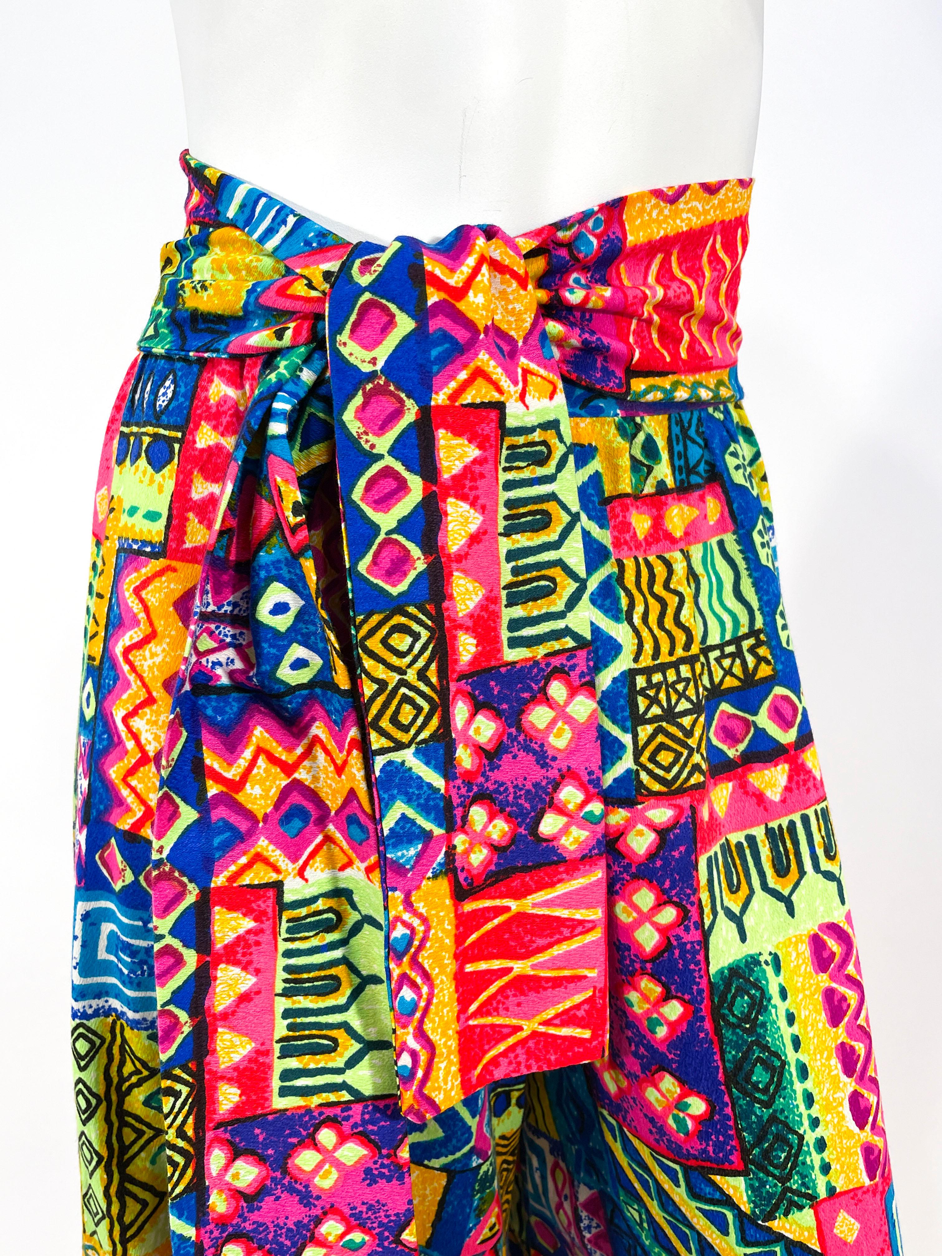 1970s customers made neon printed bark-cloth wide legged pants with matching sash that could be worn as a waist sash or a scarf. The print features an abstract geometric pattern in neon pink, blue, orange, yellow, and green. The back has a zipper