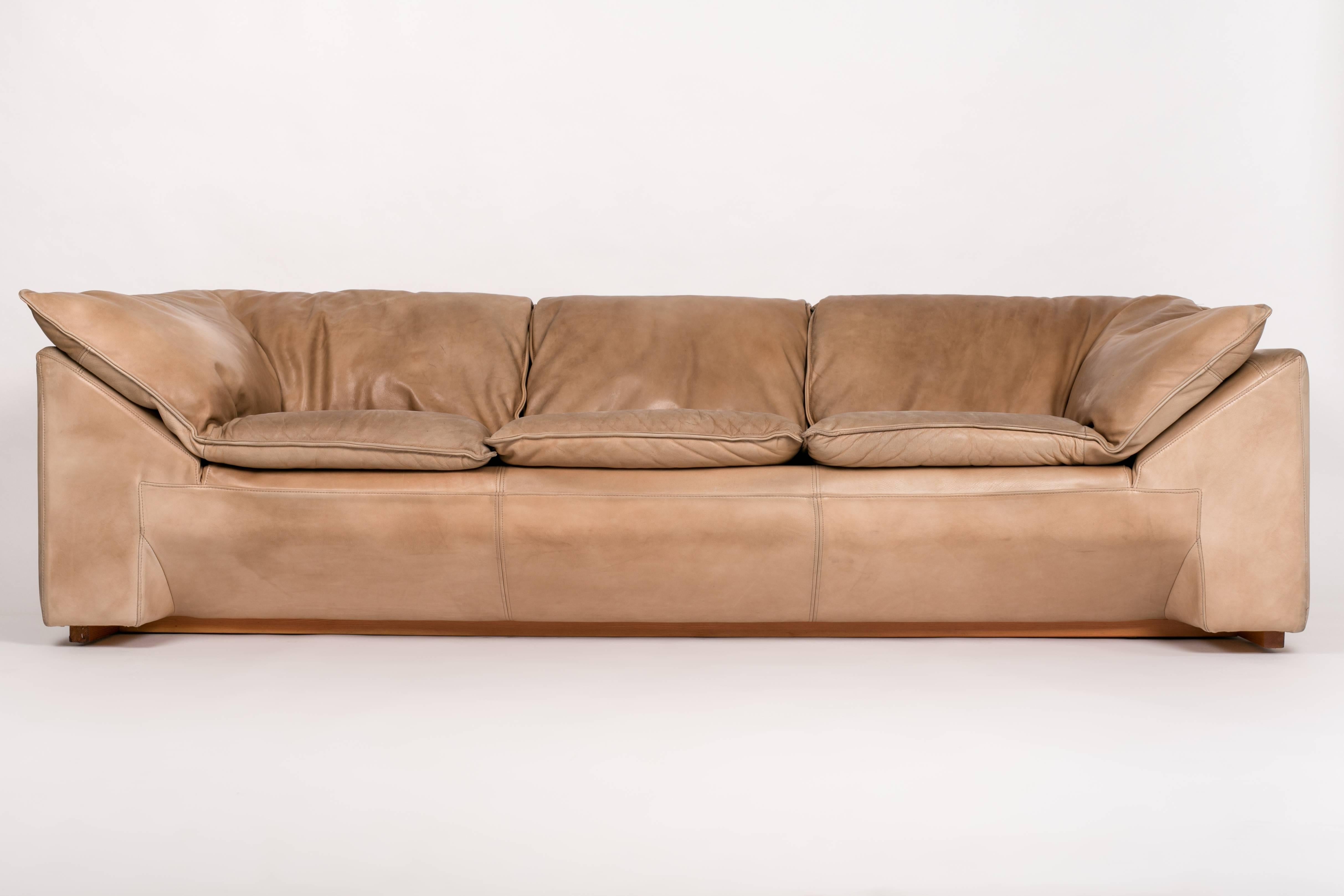 A generous, three-seat sofa designed by Jens Juul Eilersen for his family company, Niels Eilersen in the 1970s. The sofa has an upholstered, solid wood frame on a recessed wooden base. The seat is defined by luxurious down cushions, stylistically