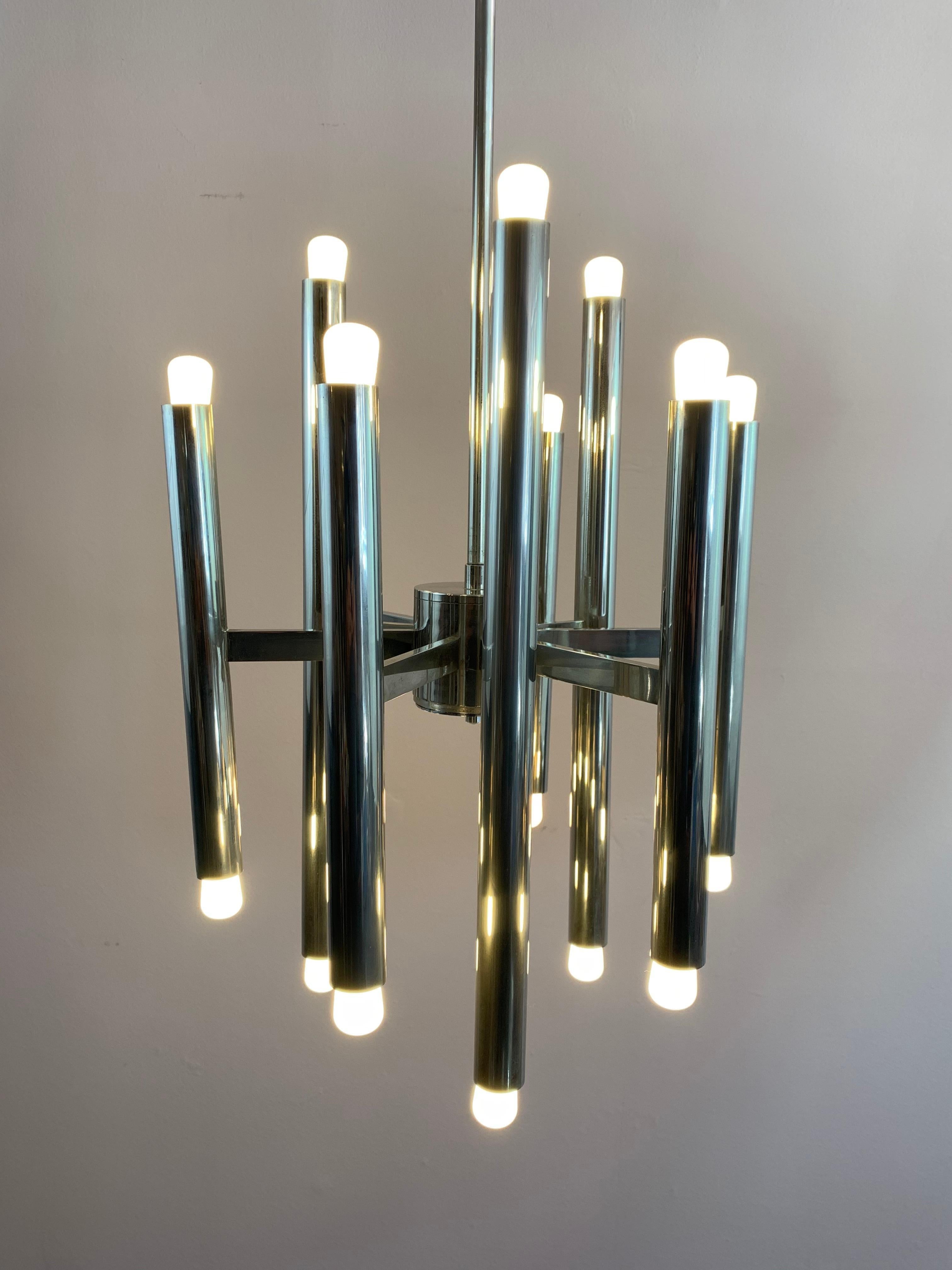 A striking 1970s brushed chrome tubular nine-arm hanging light designed by Gaetano Sciolari for Boulanger. 18 E17 screw-in bulbs are required for the light. One bulb at the top and bottom of each tube. The height is adjustable by either shortening