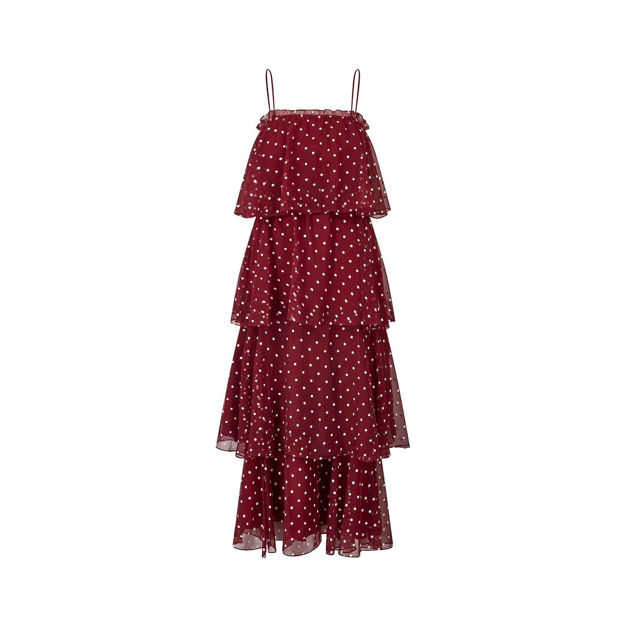 Unusual late 1970s burgundy and white polka dot tiered dress by Norman Berg.  It consists of an under skirt with a wide polka dot flounce making up the bottom or 4th tier.  The second element is a shorter top dress which slips on over the head with