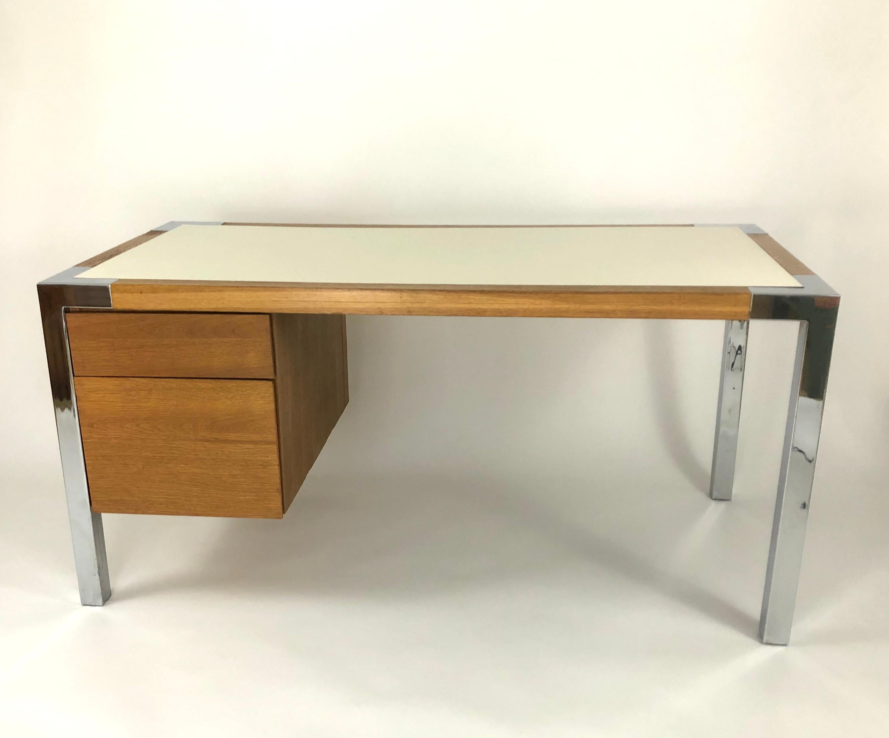 A beautifully made and stylish 1970s desk in oak with chrome trimmed corners and chrome square section legs, of rectangular form with two graduated drawers on the left hand side and a cream colored formica top. Well proportioned, very sturdy, with