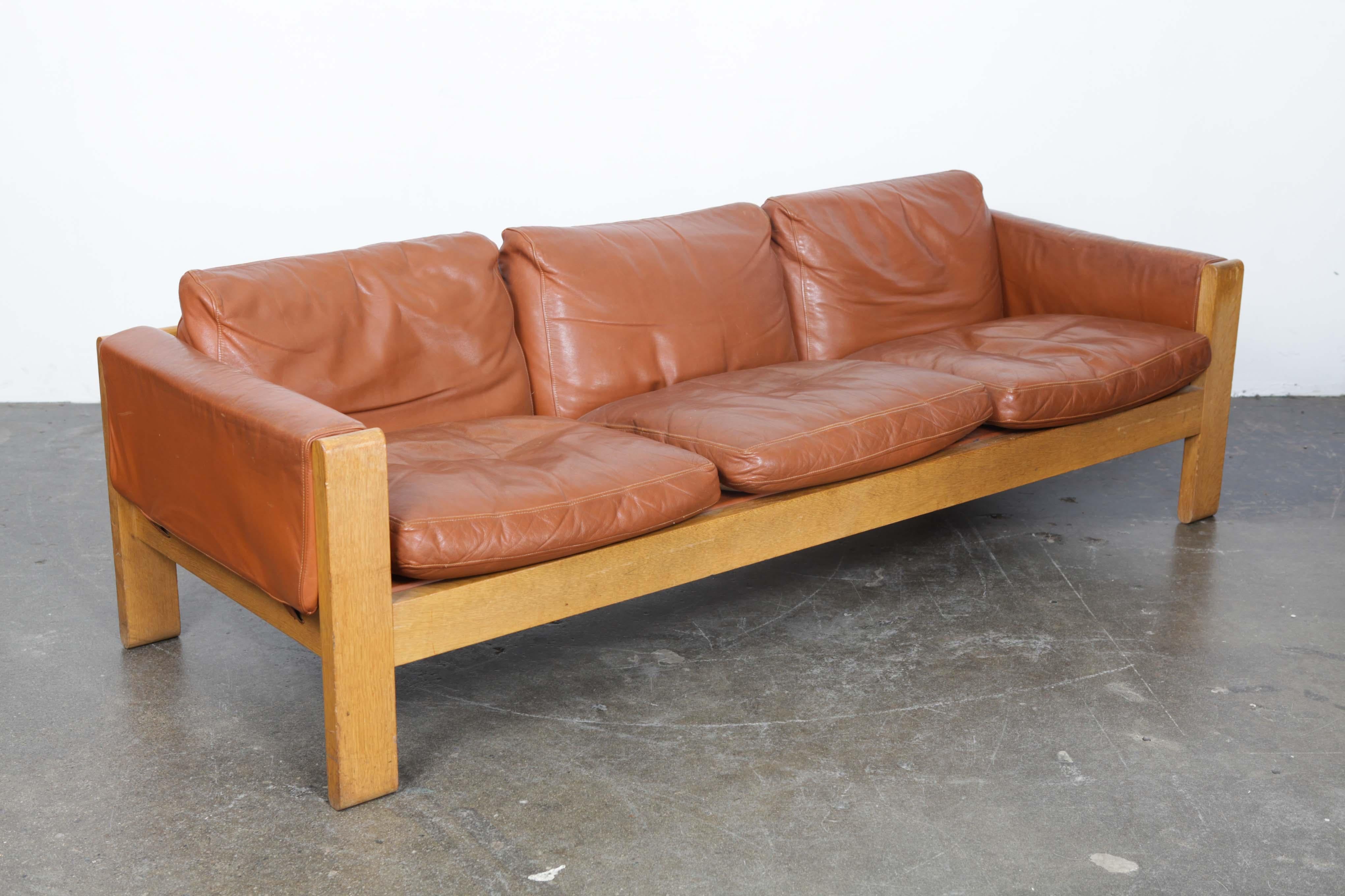 Midcentury sofa in cognac leather with loose cushions and an oak wooden block frame, produced by OPE, Sweden, 1970s. Original leather has no tears or cracks and shows a nice patina, consistent with age. Imported from Sweden to Los Angeles and kept