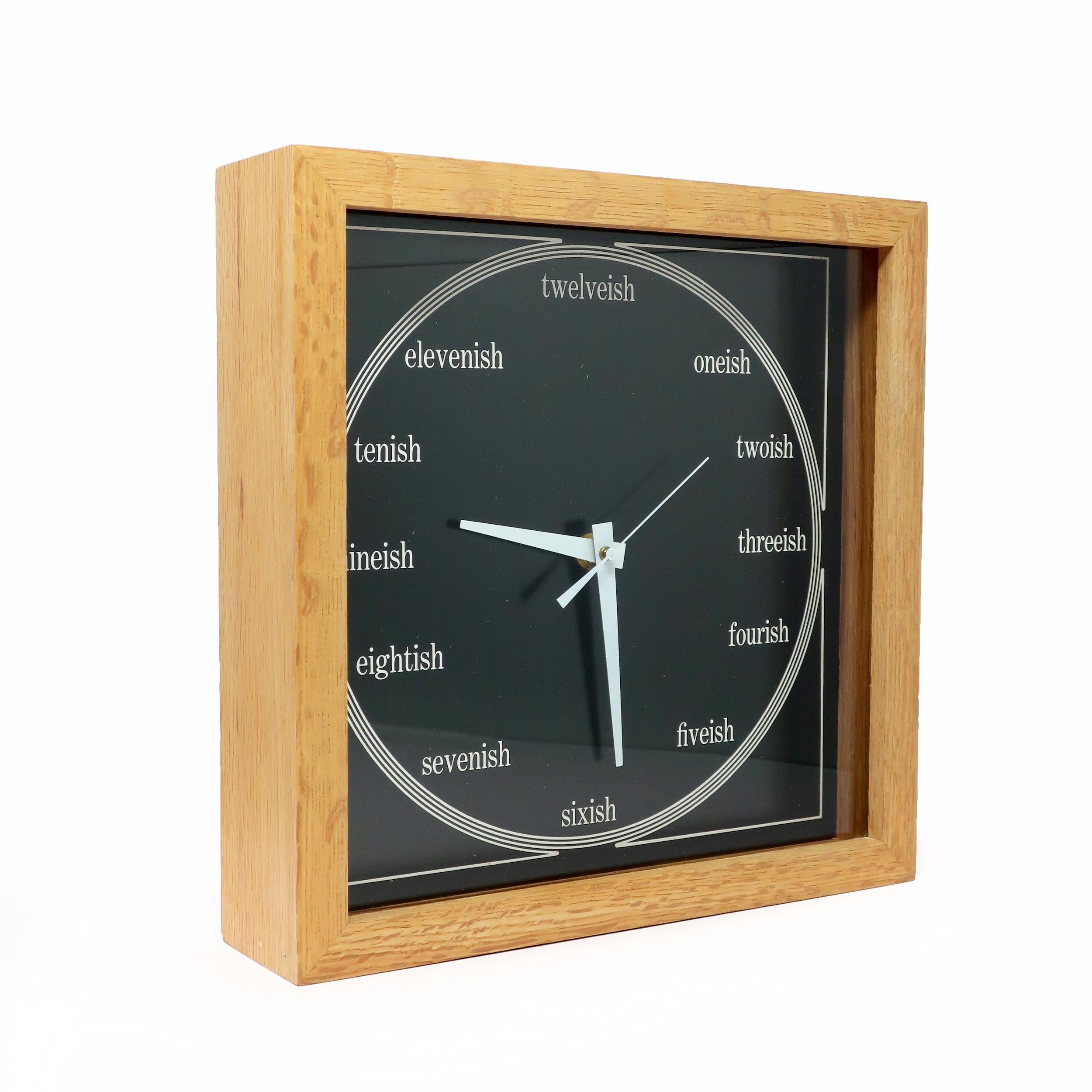 A fun wall clock by Los Angeles based clockmaker Bill Miller with a light wood frame, black face, white hands, and an 