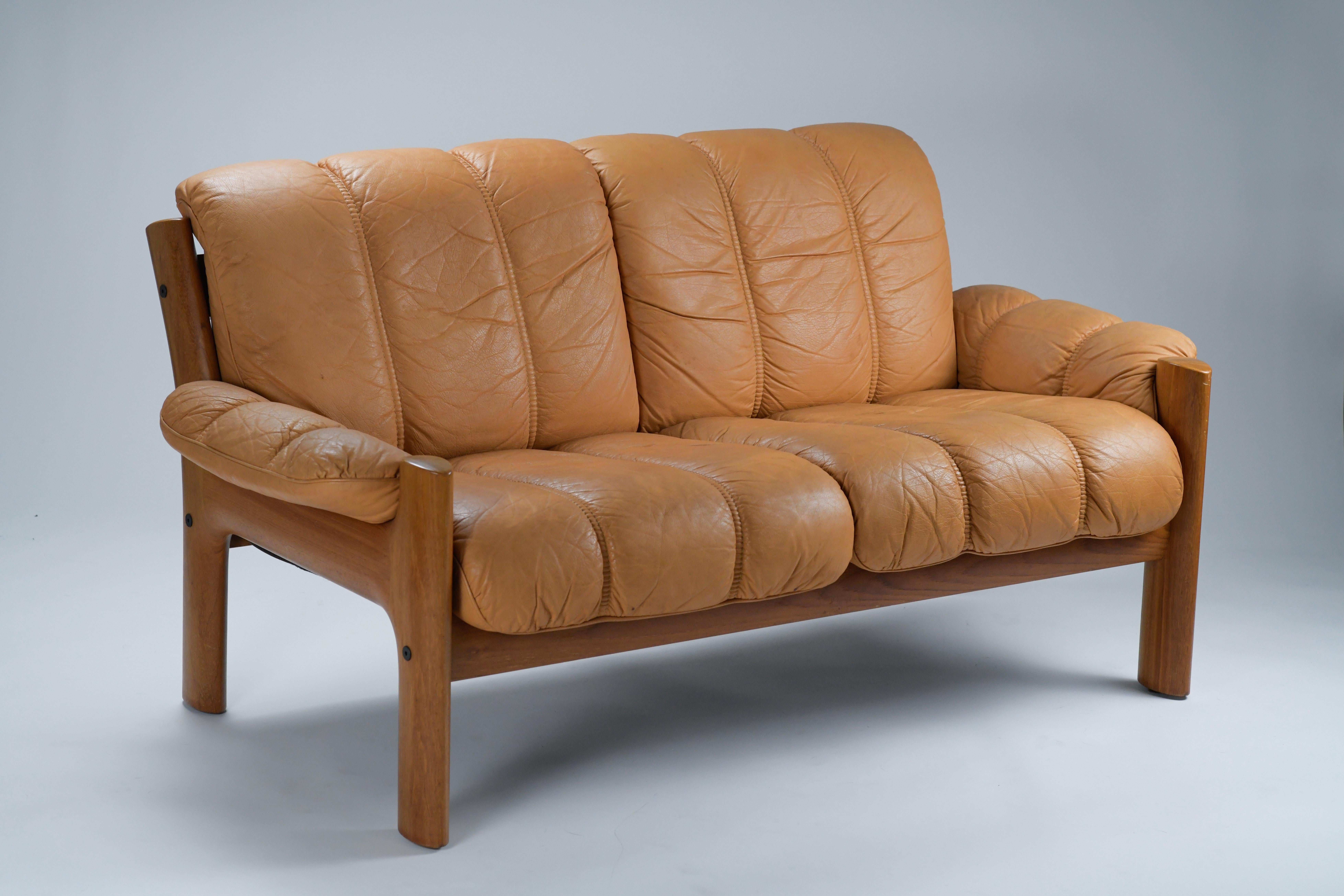 1970s mid century modern Burnt Orange leather loveseat by Ekornes. This two seaters sofa was designed and manufactured by Ekornes in Norway in the early 70s. This incredibly comfortable sofa has an organic profile with beautiful curves on its teak