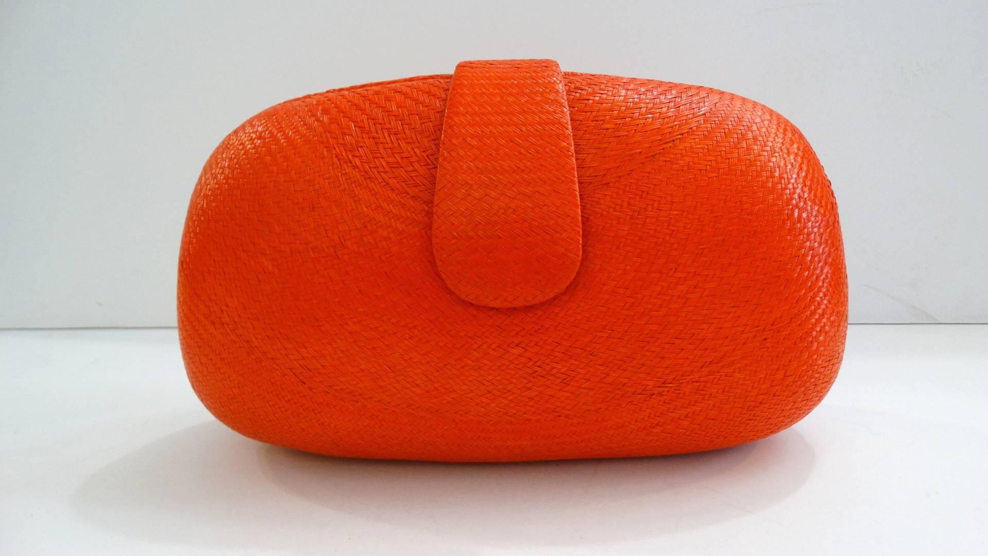 Adorable 1970s orange rattan bag! Tightly woven glossy rattan material in a summery orange color. Bag unsnaps to reveal a fully lined cloth interior. Comes with woven rope strap in a matching orange color that can be tucked in for wear as a clutch.