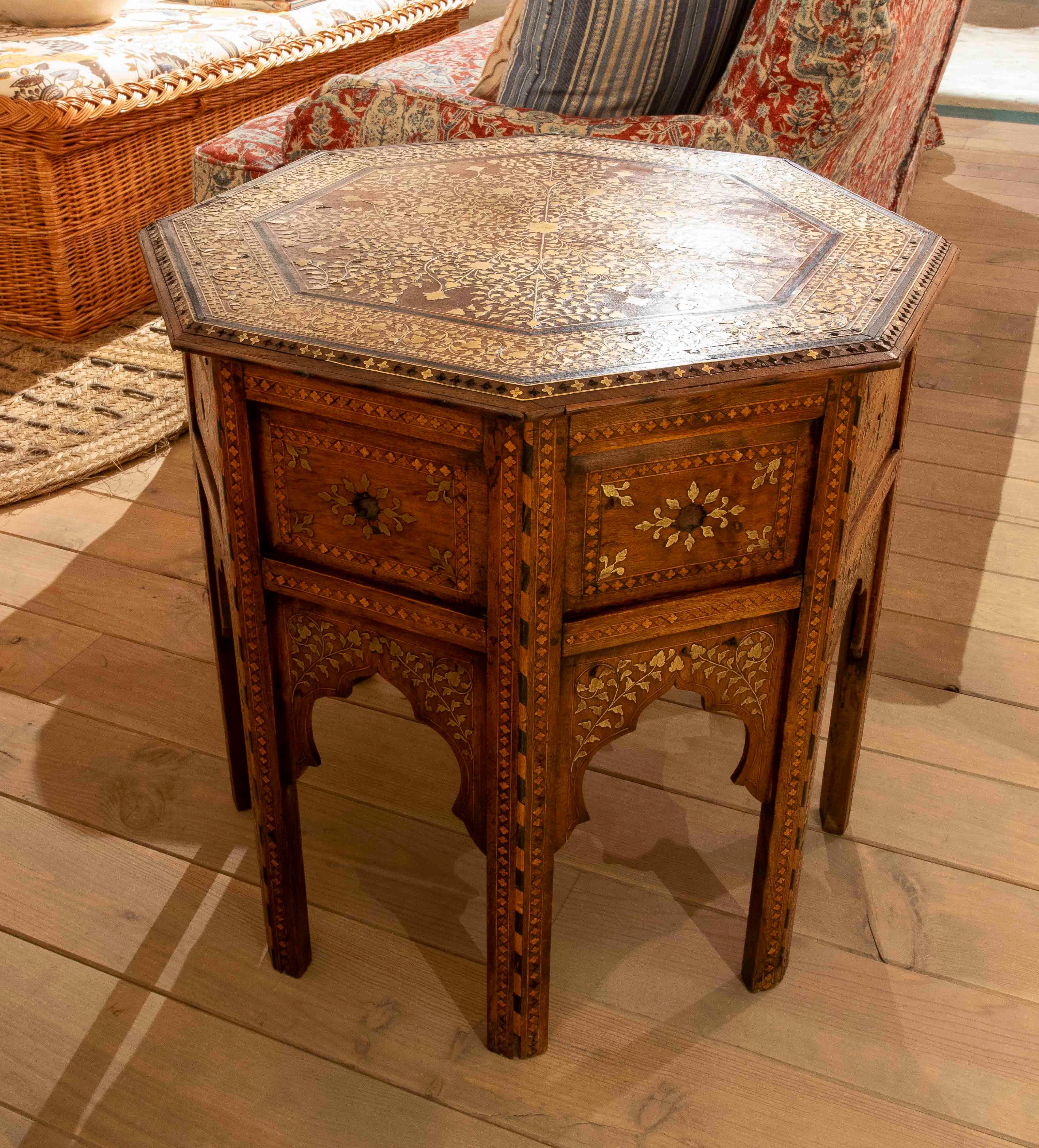 Exquise table octogonale en bois finement travaillé avec des marqueteries de nacre, de laiton et de bois exotiques. Chaque surface présente des motifs floraux et géométriques complexes d'inspiration orientale, exécutés avec une précision artisanale