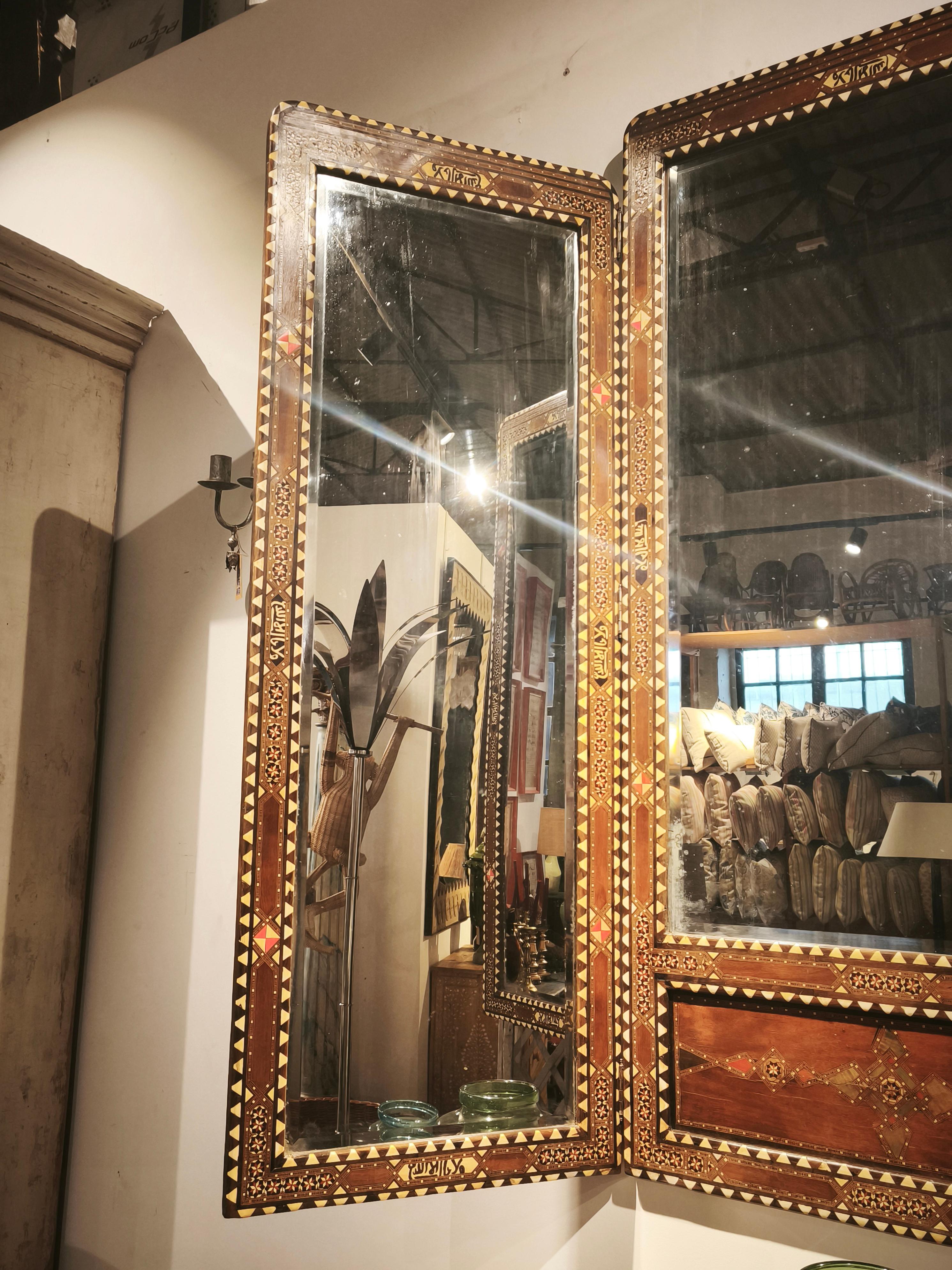 Uno spettacolare specchio trittico con cornice in legno impreziosita da intarsi in Wood. Ogni pannello presenta una squisita lavorazione artigianale ispirata all'Oriente, con motivi geometrici e floreali che aggiungono brillantezza e raffinatezza.