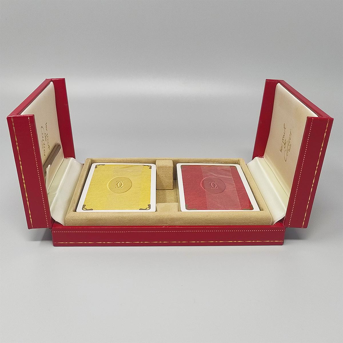 1970s Original astonishing playing cards box by Cartier with is red leather original box 2-doors case . The box is lined in silk, stamped with the Les Must de Cartier logo and includes two packs of cartier pocker cards (still sealed) and the