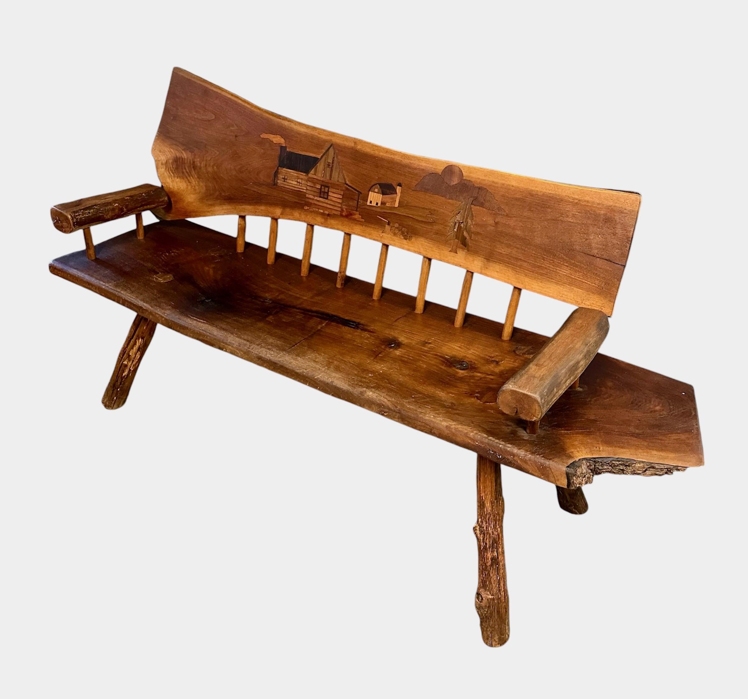 Experience the beauty and craftsmanship of this 1970s Outside Artist Country Solid Slab Bench. Handcrafted and featuring a stunning marquetry barn scene, this solid wood bench is a unique and functional piece of art. Add a touch of rustic charm to
