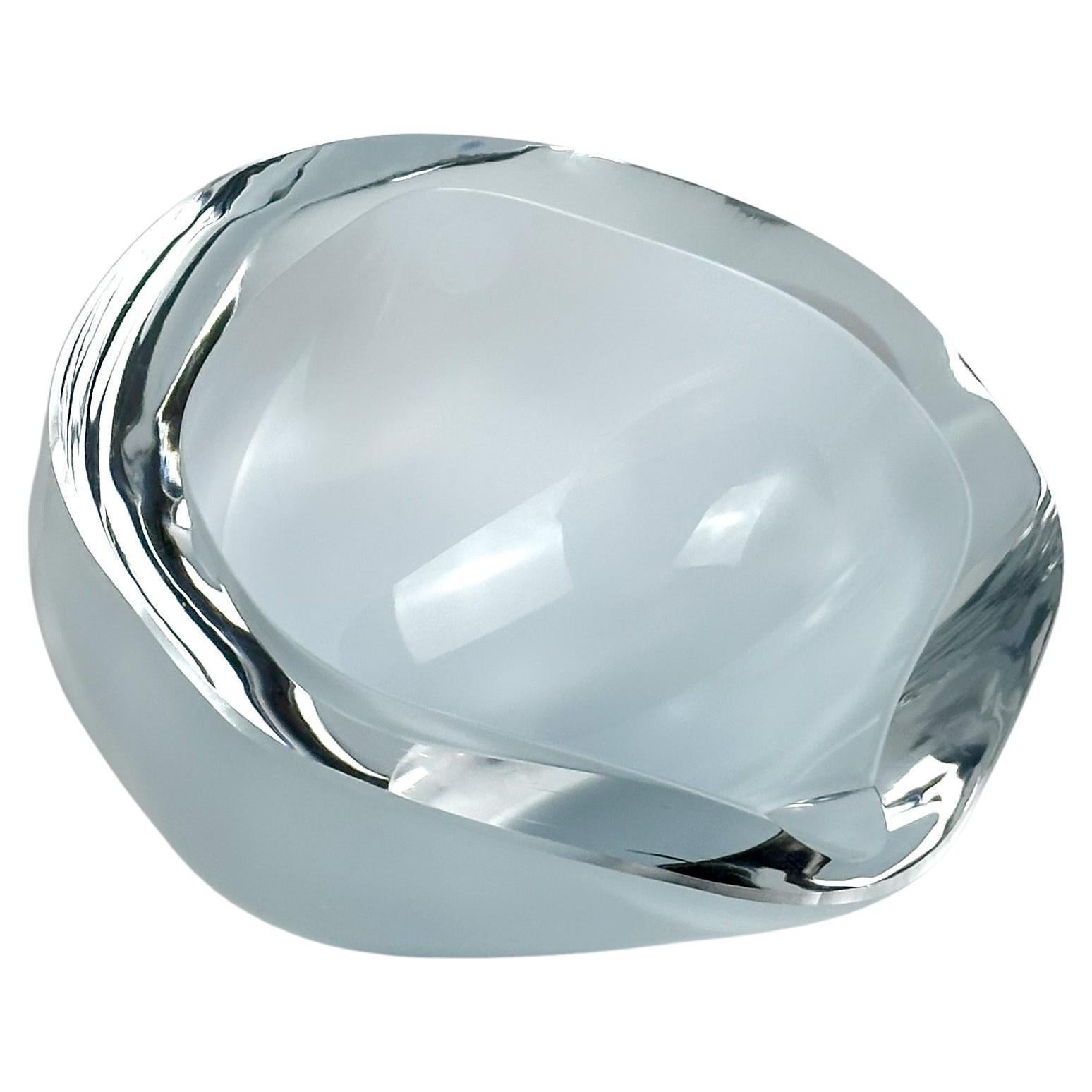 A unique geode-style glass dish, crafted from crystal-clear optical glass. Its semi-angular oval form features a gently curved back, while the surround is sharply cut at a 45-degree angle, evoking the shape of a majestic sea  shell; a modernist