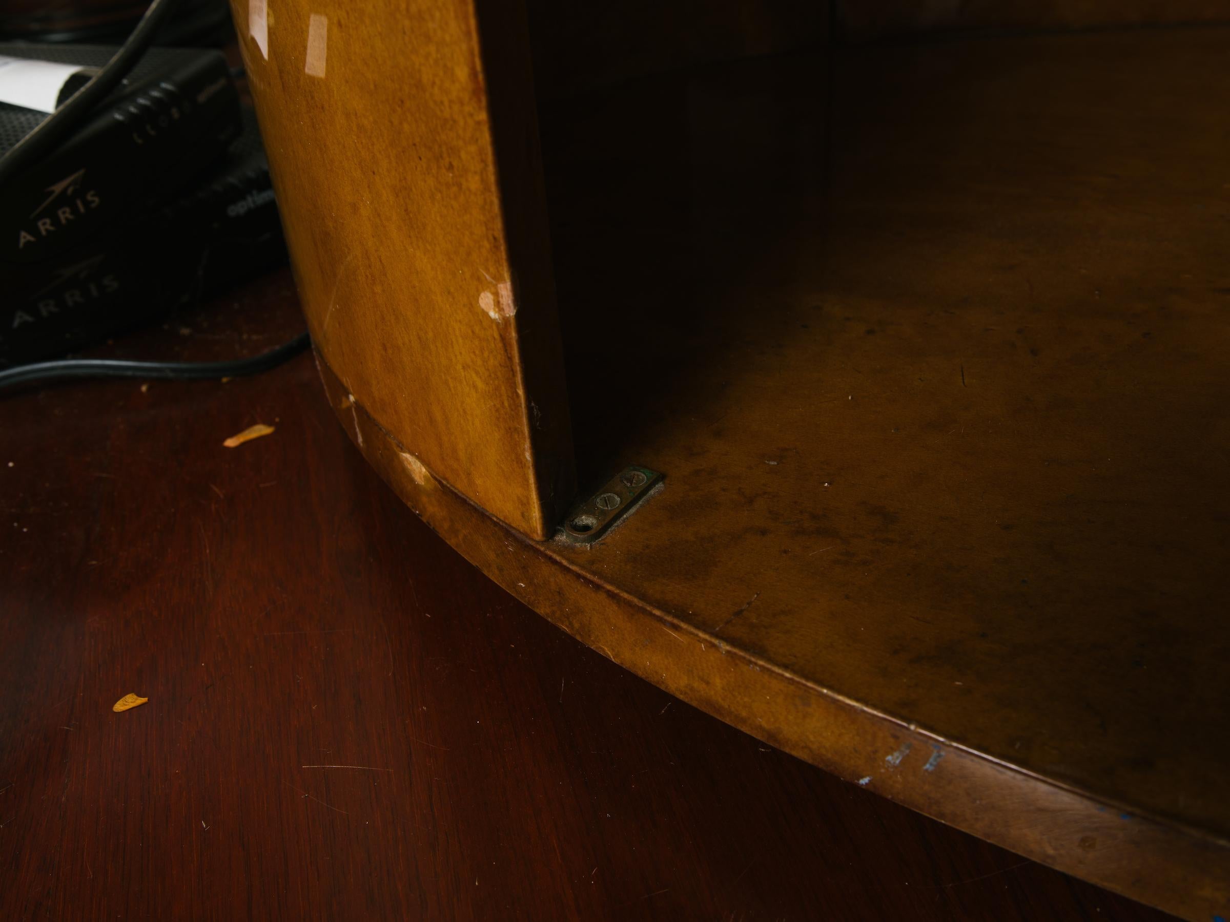 1970s oval goatskin bookcase with glass shelves. This piece originally had doors on it. The hardware is still there. It has a hole cut in the back, needs a decorative brass piece applied to it to hide the cut-out. Some chips in the lacquer.