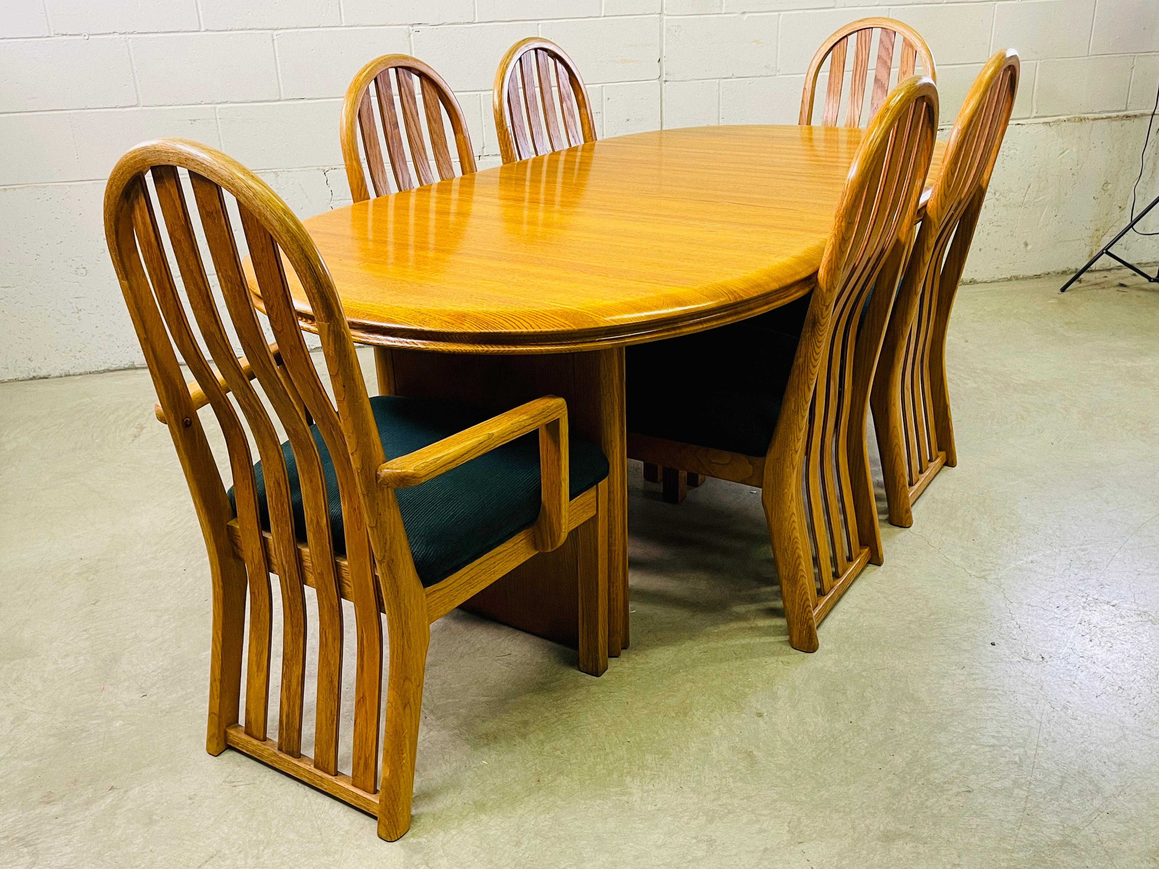 Vintgae 1970s solid oval oak wood dining table with 6 chairs. The table comes with one additional 24”W board. The table closed is 56”L. The set has two arm chairs which measure 23”L x 19”W x 40”H. This set is a sturdy solid oak with the original