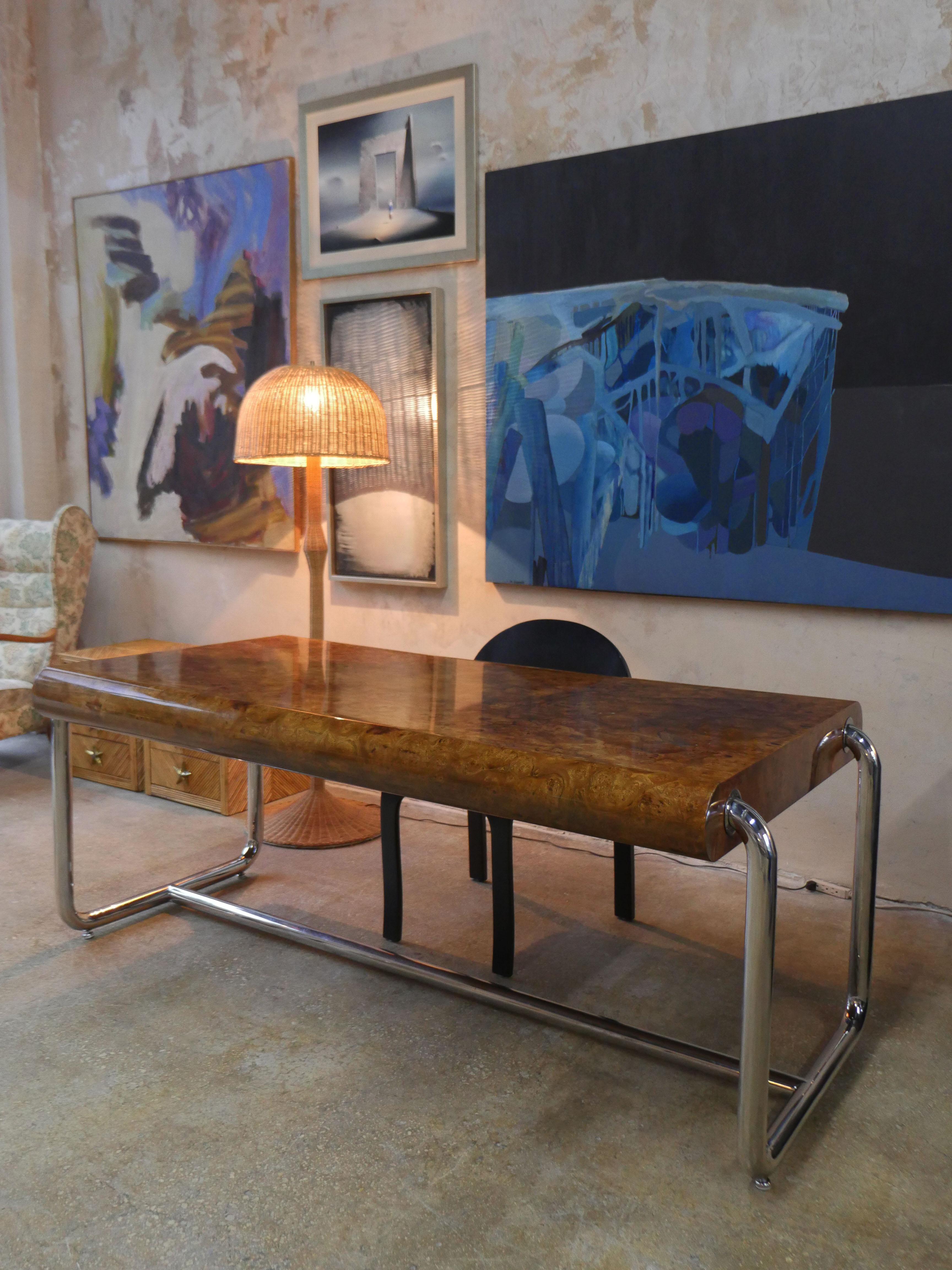 1970s designer desk from the Pace Collection, featuring a sleek rectangular lacquered olive burl wood top with a rounded bullnose front edge. The piece is anchored by polished chrome steel legs joined by a sculptural H-form stretcher, offering a
