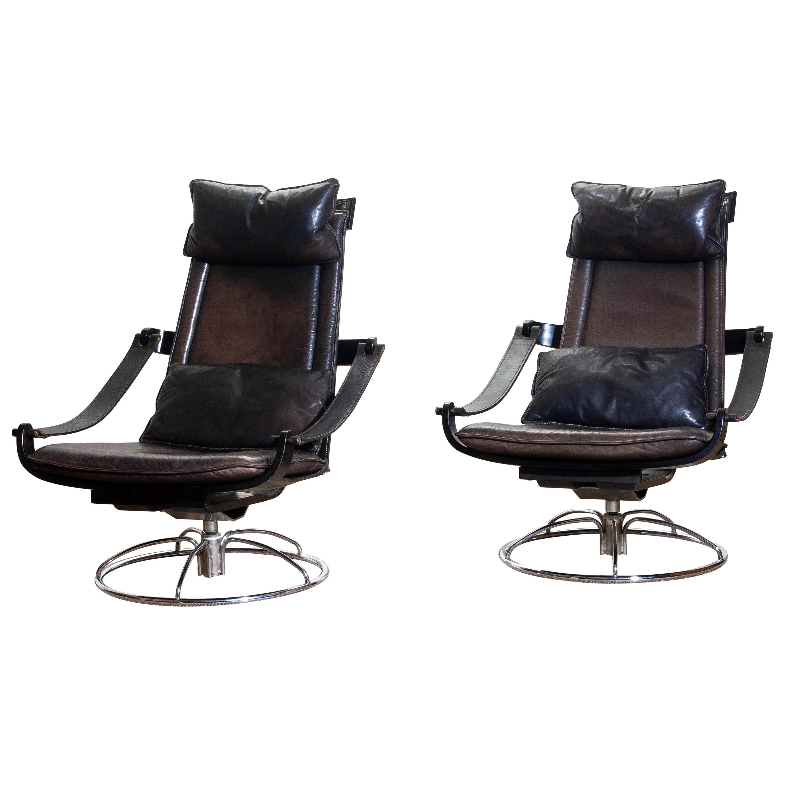 Extremely beautiful and artistic set of two swivel easy / lounge chairs designed by Åke Fribytter for Nelo, Sweden.
These high quality chairs features a plywood frame and brown leather cushions and a chromed metal base.
The armrests are made of