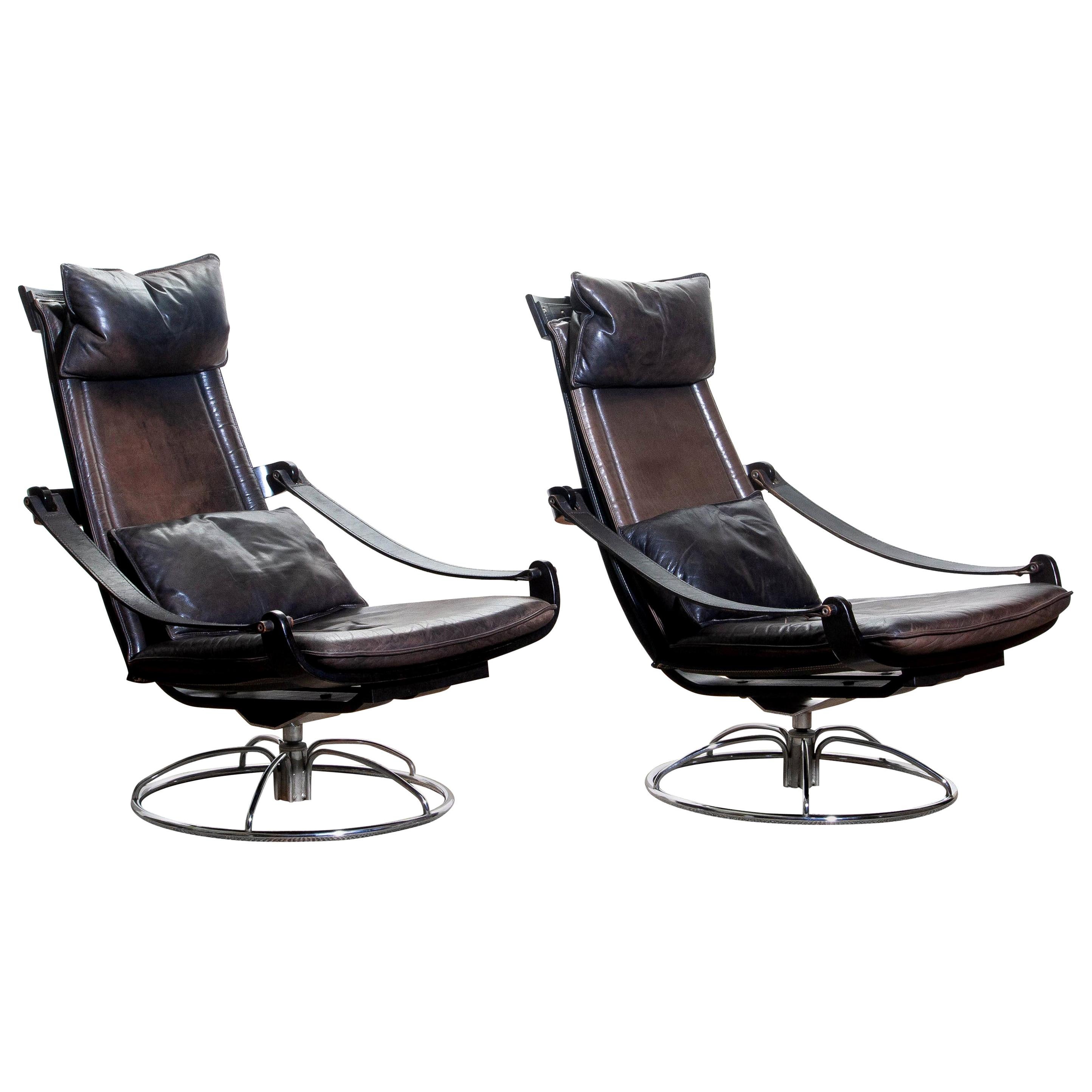 Extremely beautiful and artistic set of two swivel easy / lounge chairs designed by Åke Fribytter for Nelo, Sweden.
These high quality chairs features a plywood frame and brown leather cushions and a chromed metal base.
The armrests are made of