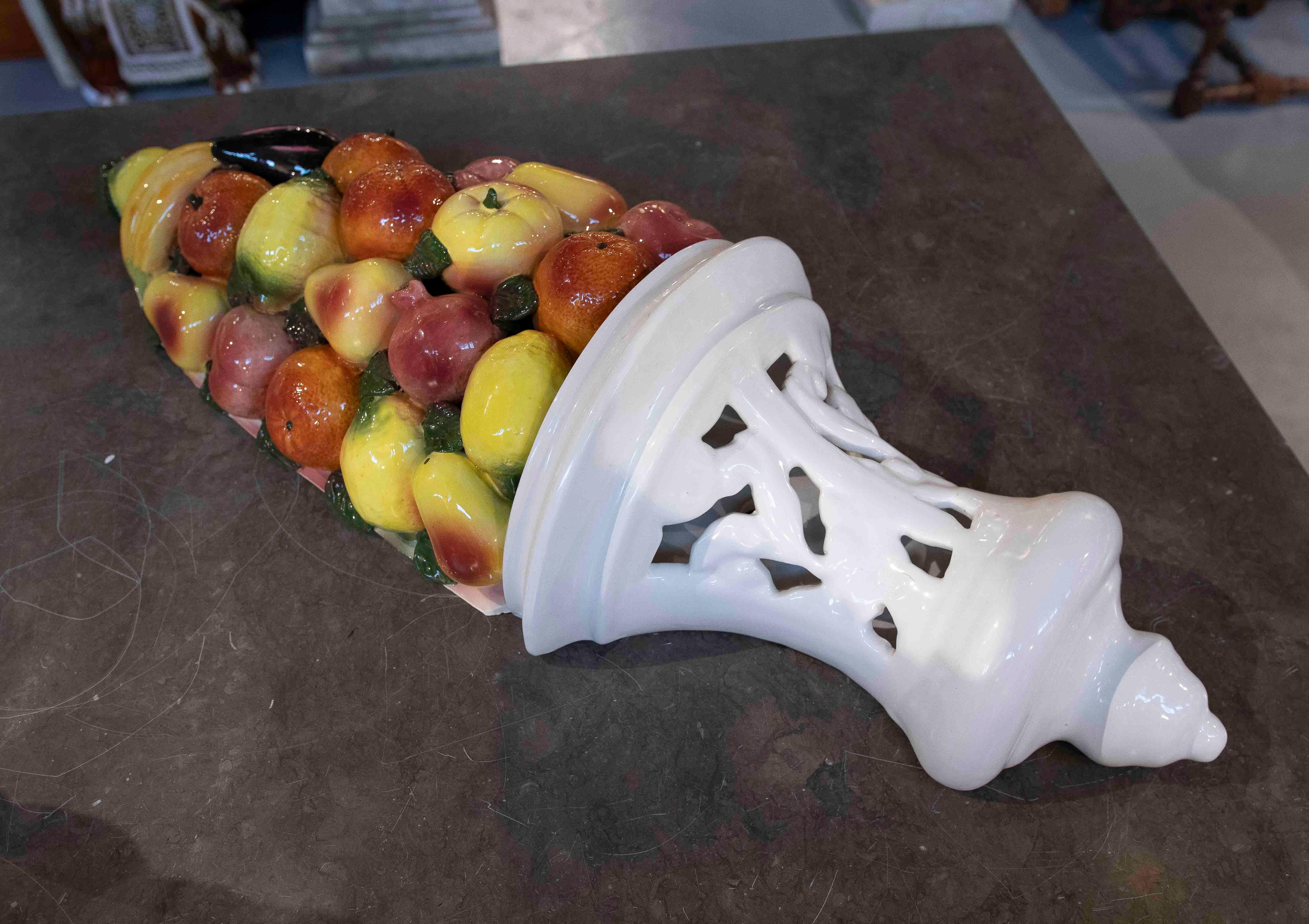 Exquise paire d'appliques murales décoratives, fabriquées en céramique blanche avec un design ajouré et surmontées d'une composition colorée de fruits vernissés. Ces pièces se distinguent par leur style classique et leur palette de couleurs