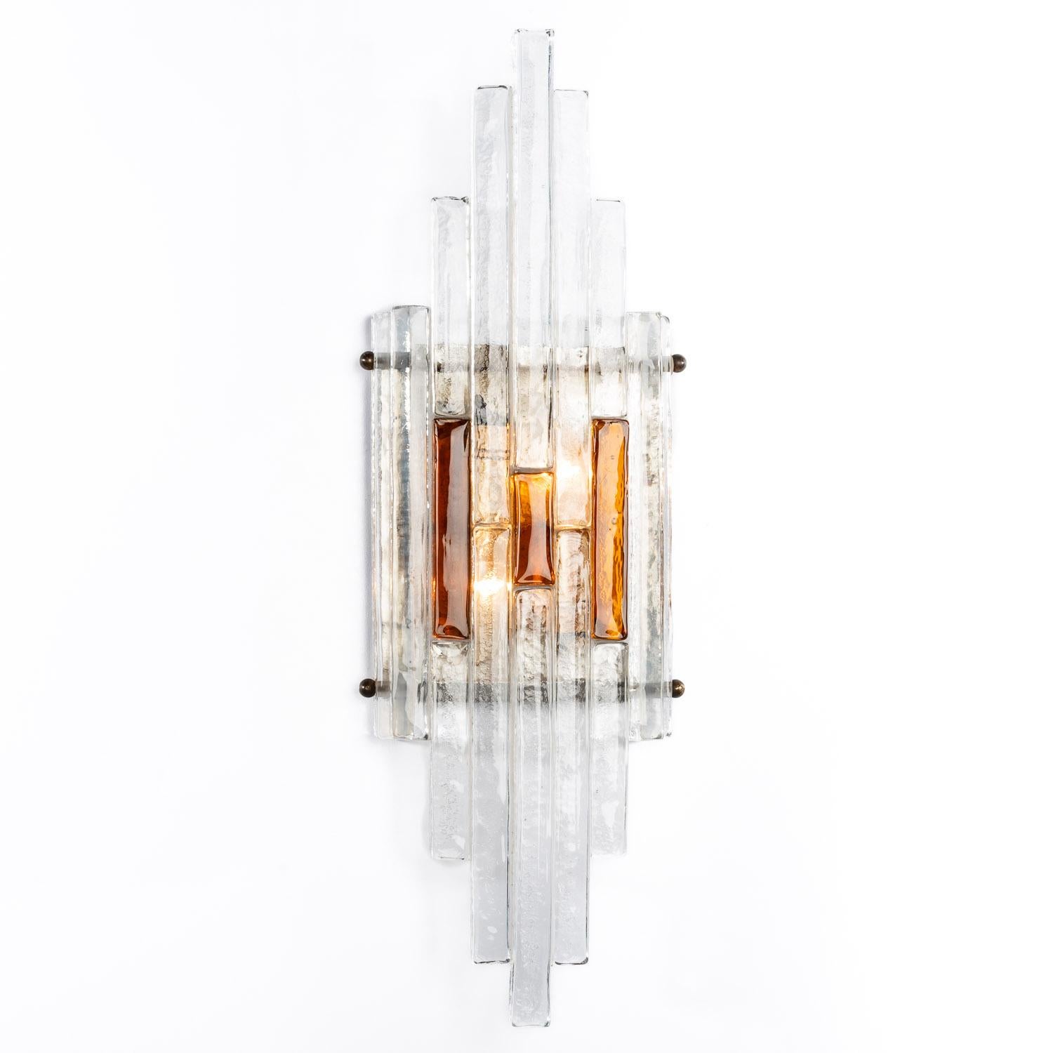A beautiful pair of scones with each 7 kilo thick bicolor Murano glass fronts. Clear and Amber handblown raw strips and a steel back plate. Each hold two E14 sockets.
 