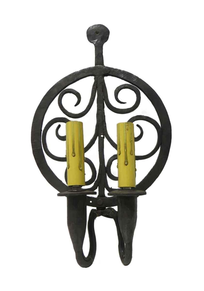 1970s Colonial style double candlestick arm sconces, hand forged wrought iron featuring a swirl circular cut out back plate. These sconces are rewired and ready to ship. Priced as a pair. This can be seen at our 302 Bowery location in NoHo in