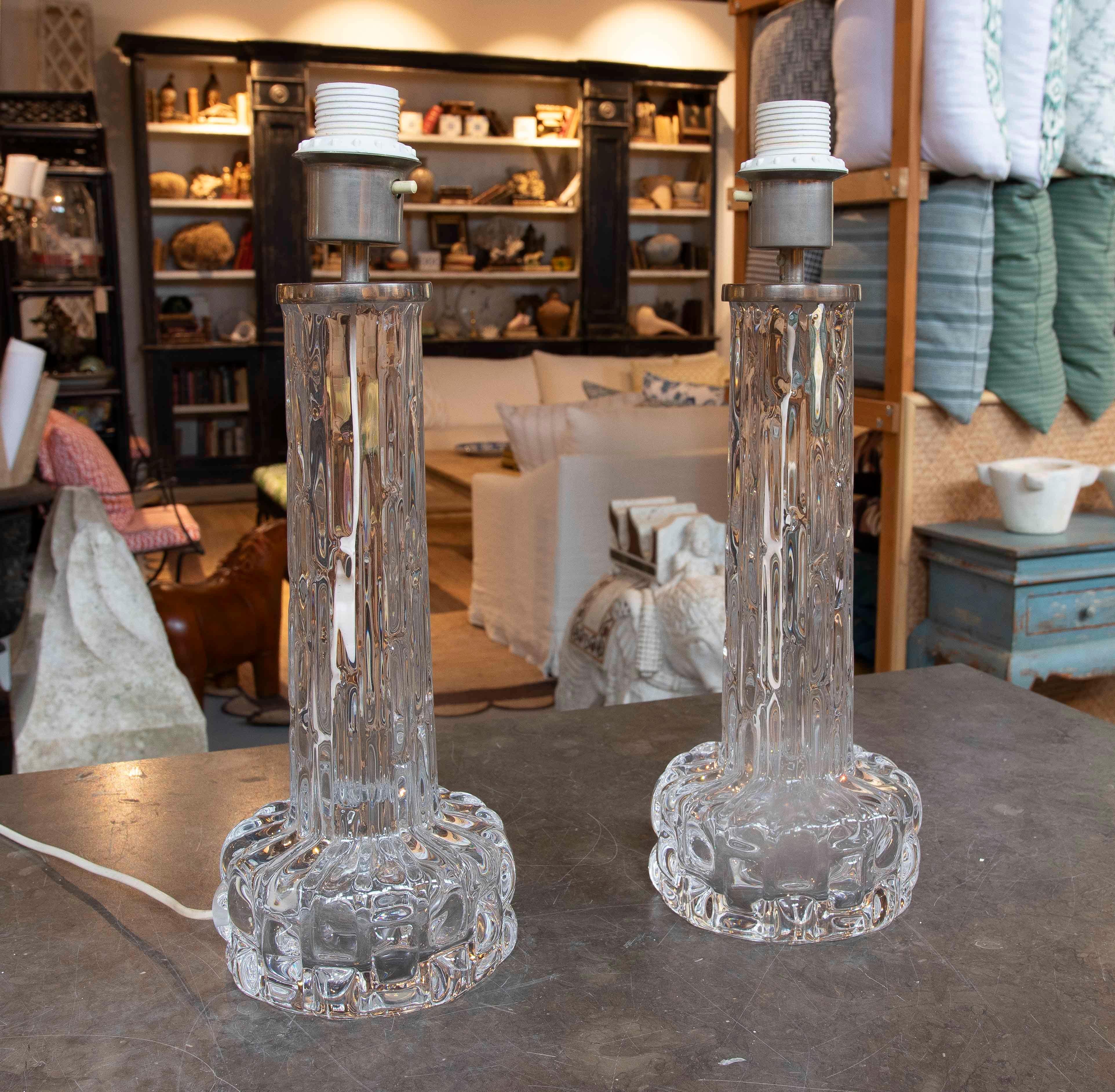 Paire de lampes de table sophistiquées en cristal taillé transparent du designer Carl Eleg, en parfait état, présentant un design cylindrique vertical qui allie élégance et présence sculpturale. Le corps présente des reliefs ondulés et des découpes