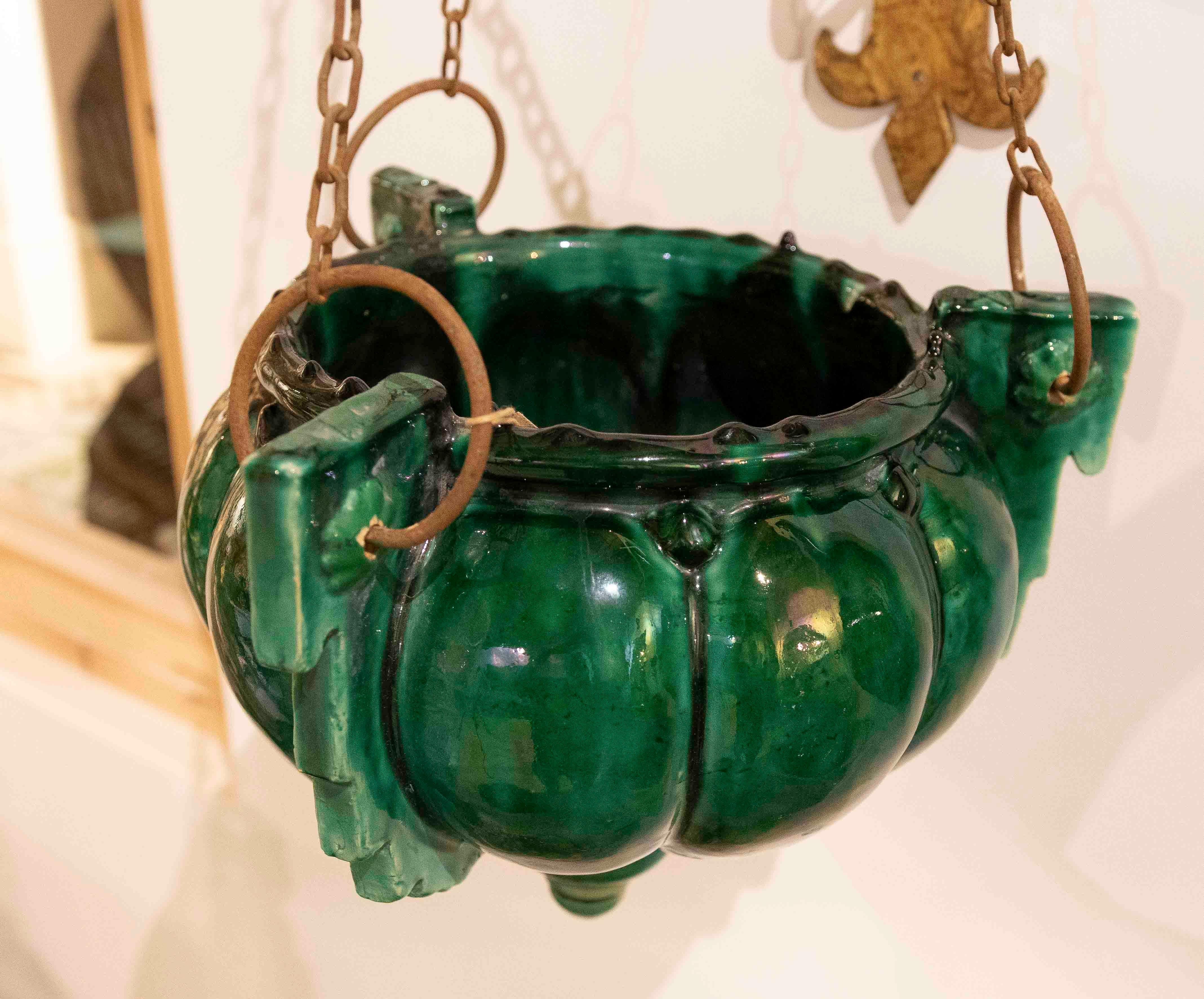 Une élégante paire de lampes suspendues du milieu du 20e siècle, fabriquées à partir de verre pressé vert émeraude intense et de supports en fer forgé finis à l'or. Chaque pièce présente une structure en chaîne qui soutient un corps en forme de