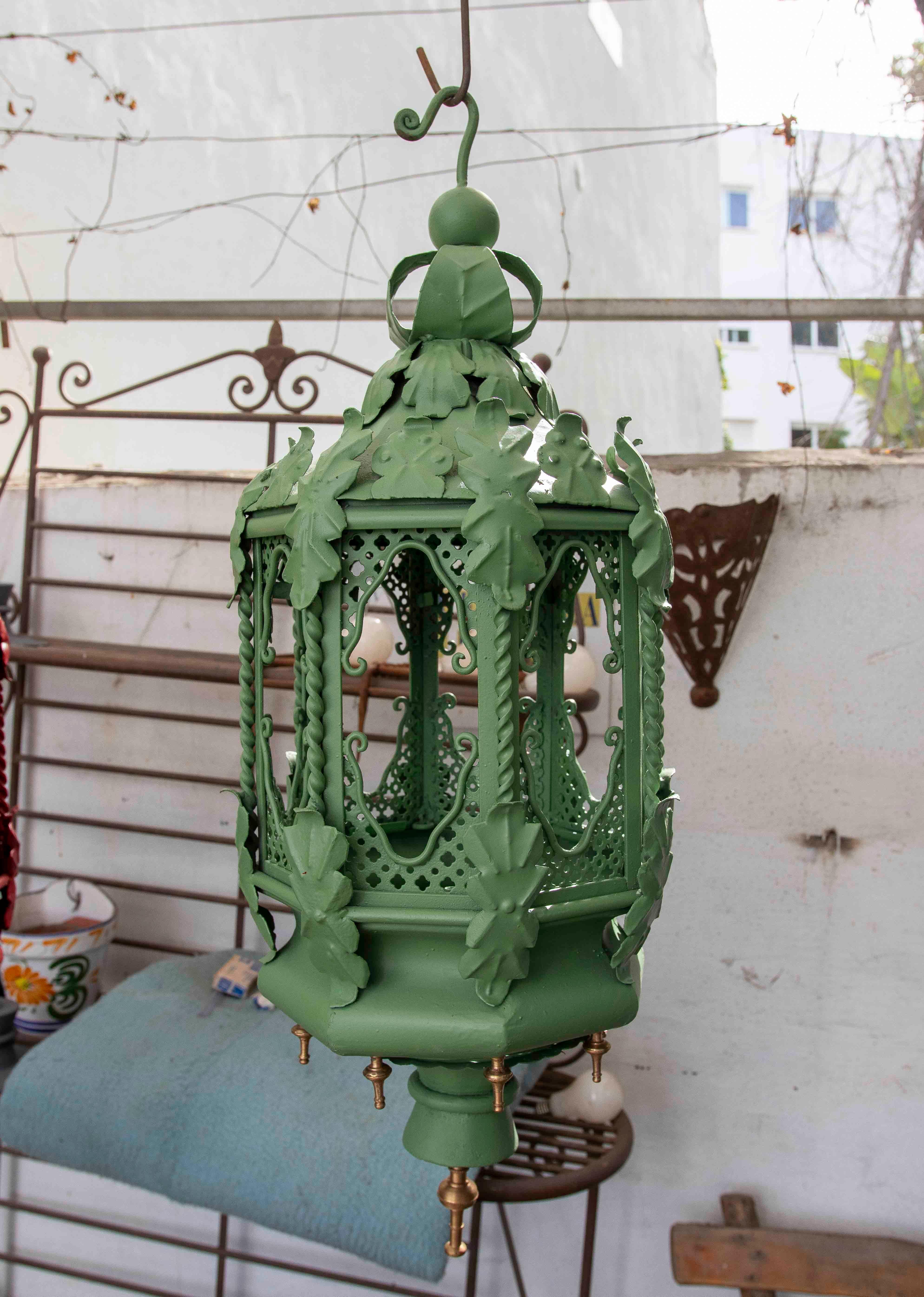 Elegantes Paar schmiedeeiserner Hängelampen in einem sanften Grünton mit einem handgefertigten Design, das ornamentale Details aus Blättern und durchbrochenen Mustern umfasst. Die sechseckige Struktur und die detaillierte Ausführung spiegeln einen