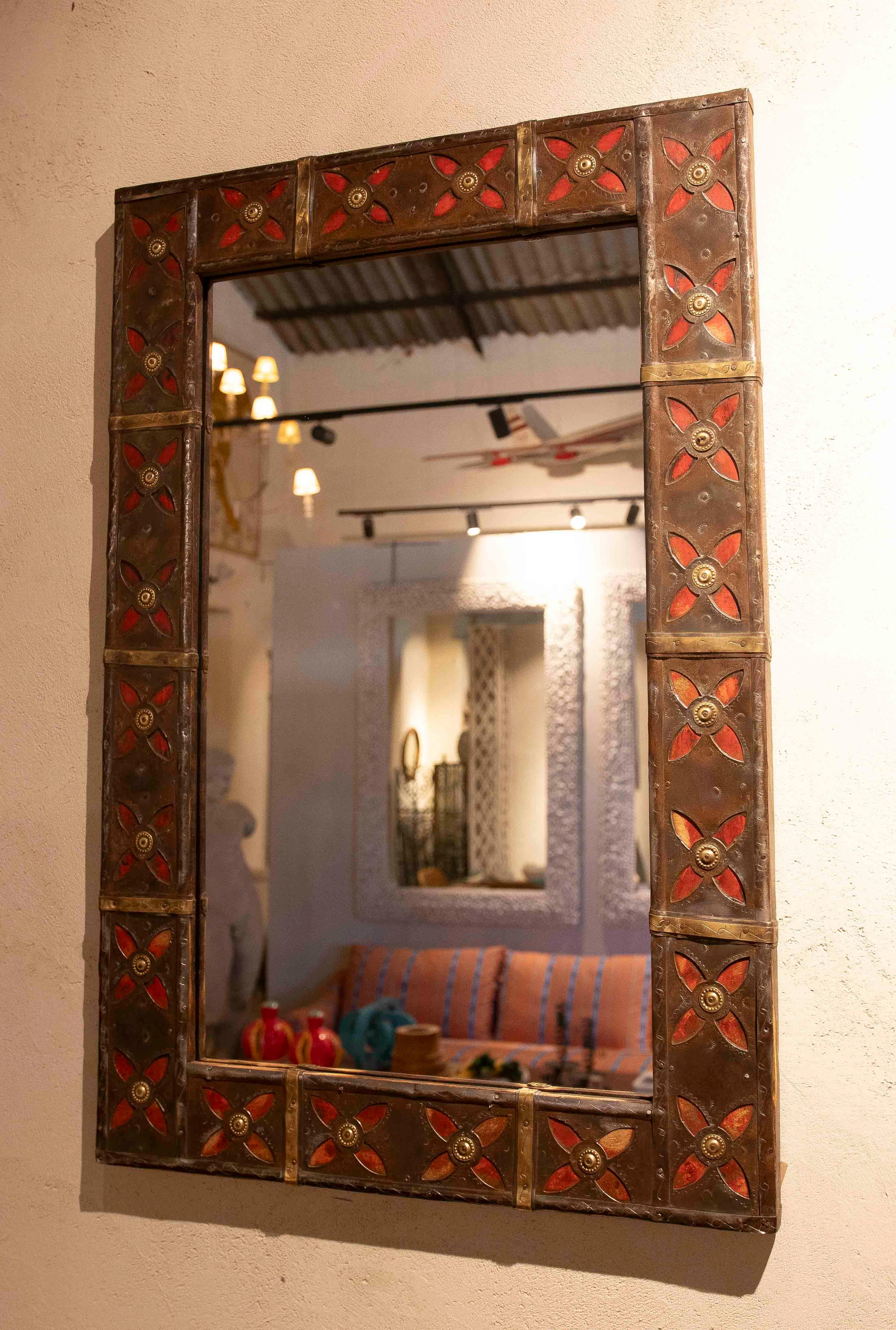 An elegant pair of handcrafted mirrors featuring wrought iron frames decorated with a geometric pattern of stylized embossed flowers. The deep red details, combined with gold appliqués in the centers, lend a vibrant and sophisticated air to each