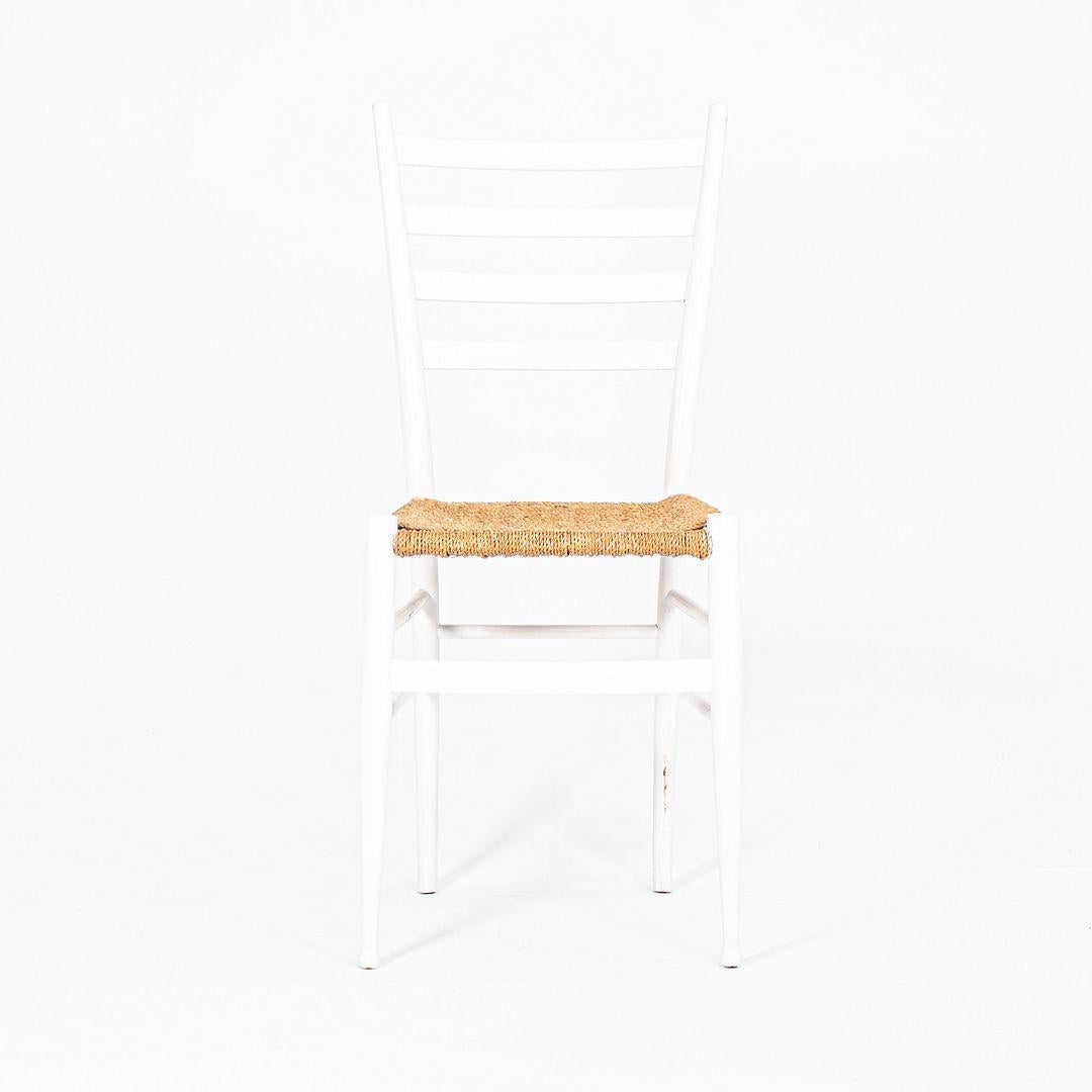 This is a pair of Italian Ladder Back white chairs, made in the style of Gio Ponti. These side chairs have a solid wood construction, white finish, tapered legs, woven rope seats, and a sleek sculptural form. 

The listed price includes two chairs