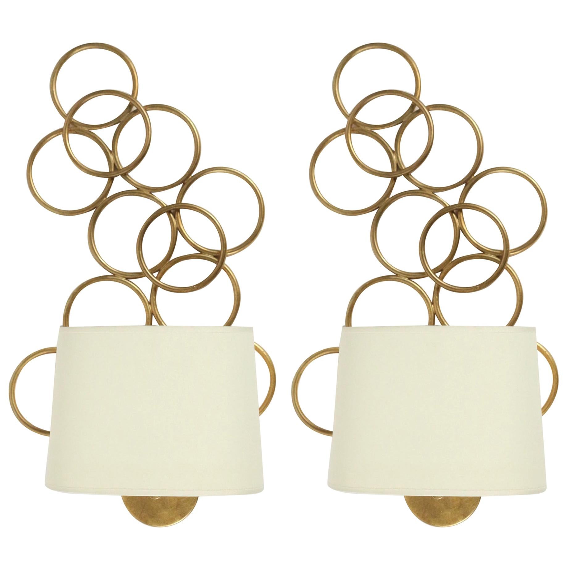 1970s pair of Maison Honore sconces.

Made of intertwined circles, made of gilded metal.
Oval lampshade made of off-white cotton.

One bulb per sconce.