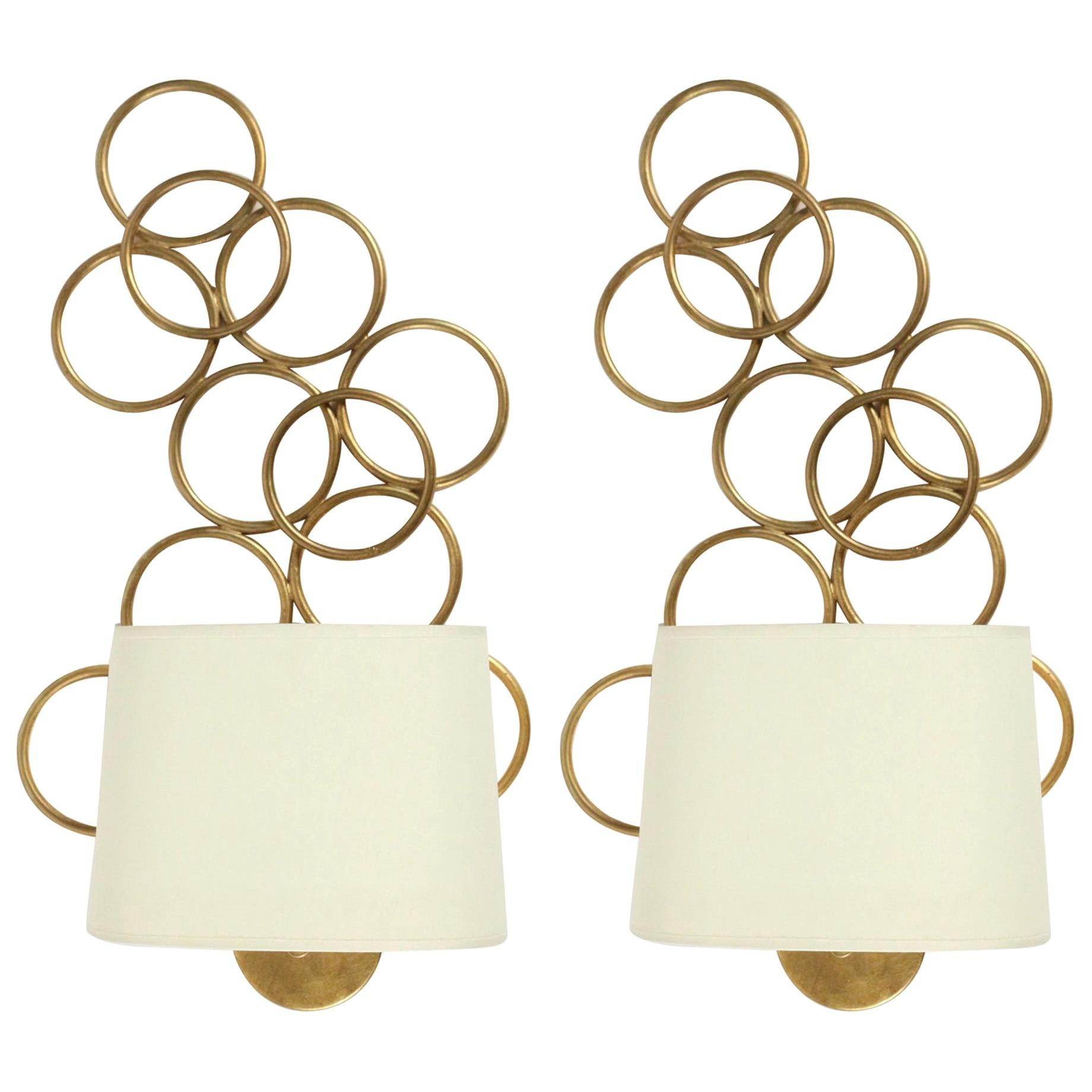1960 Paire d'appliques Maison FlorArt
Composed of a round wall support on which rests on the lower part the arm of light dressed with off-white cotton lampshade of oval shape.
On the top the wall lamp is decorated with a series of interlaced circle