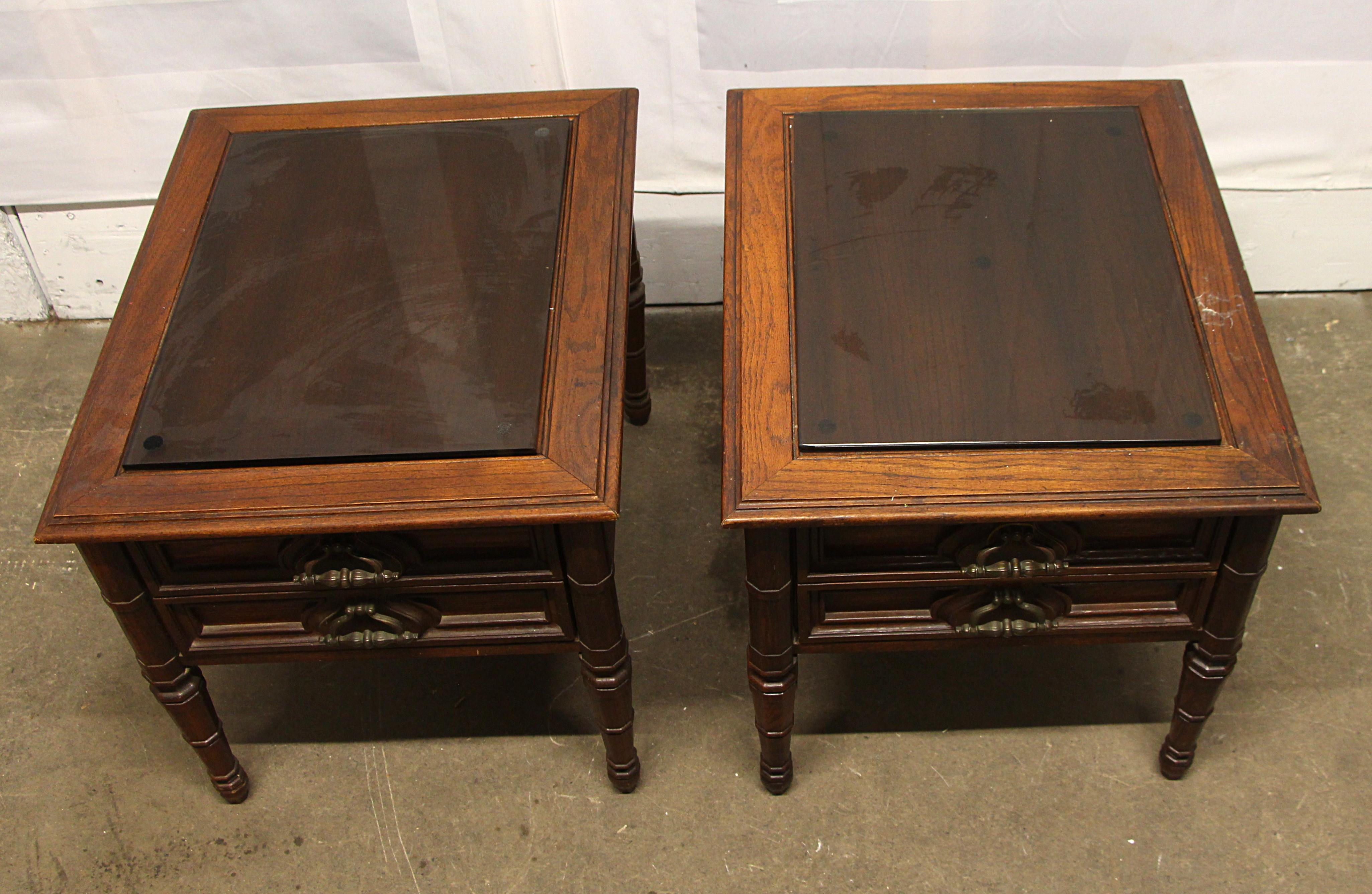 1970s dark tone carved oak single drawer side tables with double drawer pulls and glass tops. Priced as a pair. This can be seen at our 302 Bowery location in NoHo in Manhattan.