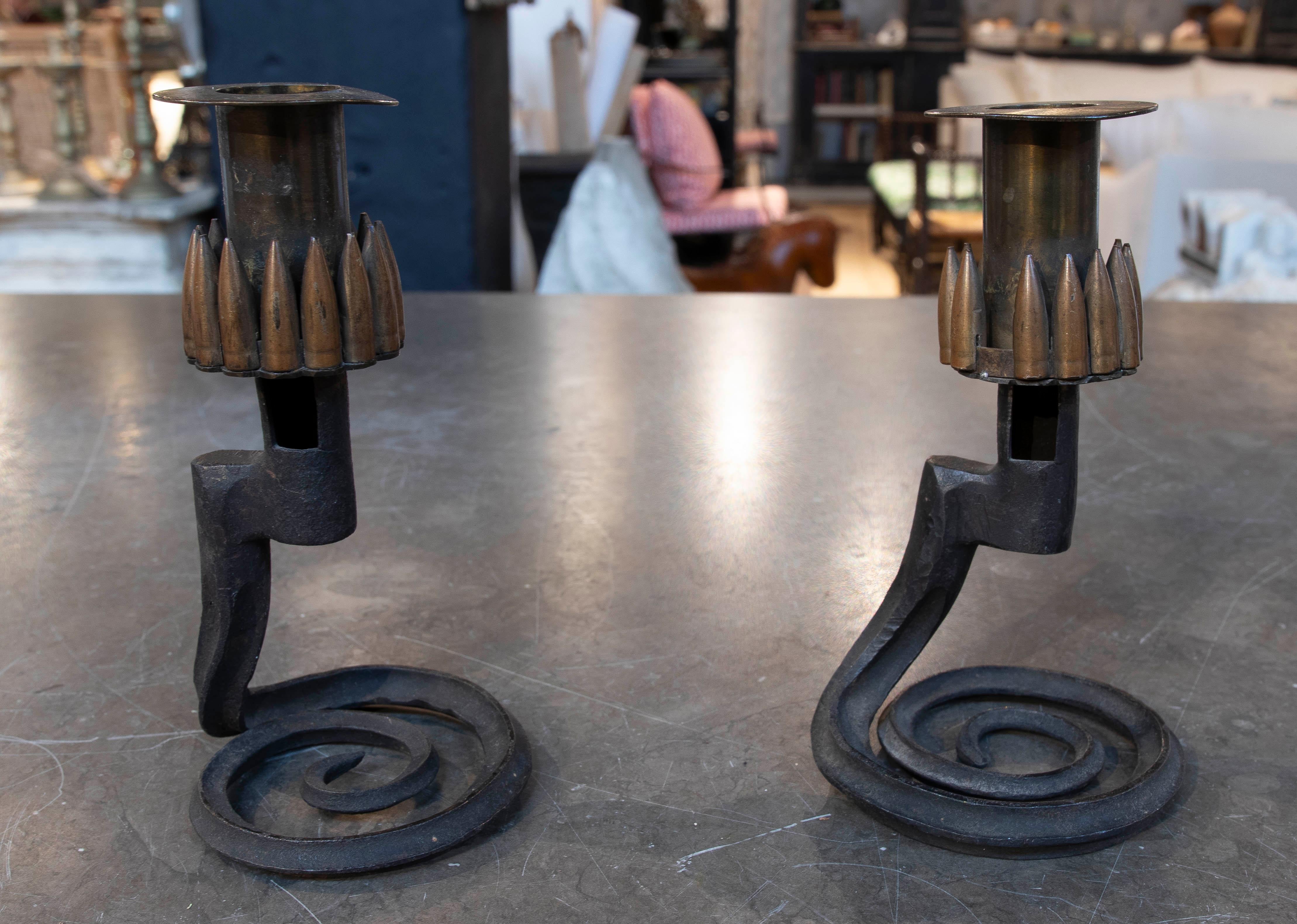 Dieses einzigartige Paar Kerzenständer kombiniert rustikale und industrielle Kunst mit einem kühnen Touch: Jeder ist mit recycelten Muscheln verziert, die sorgfältig in die Spitze integriert sind. Der spiralförmige Sockel aus Schmiedeeisen verleiht