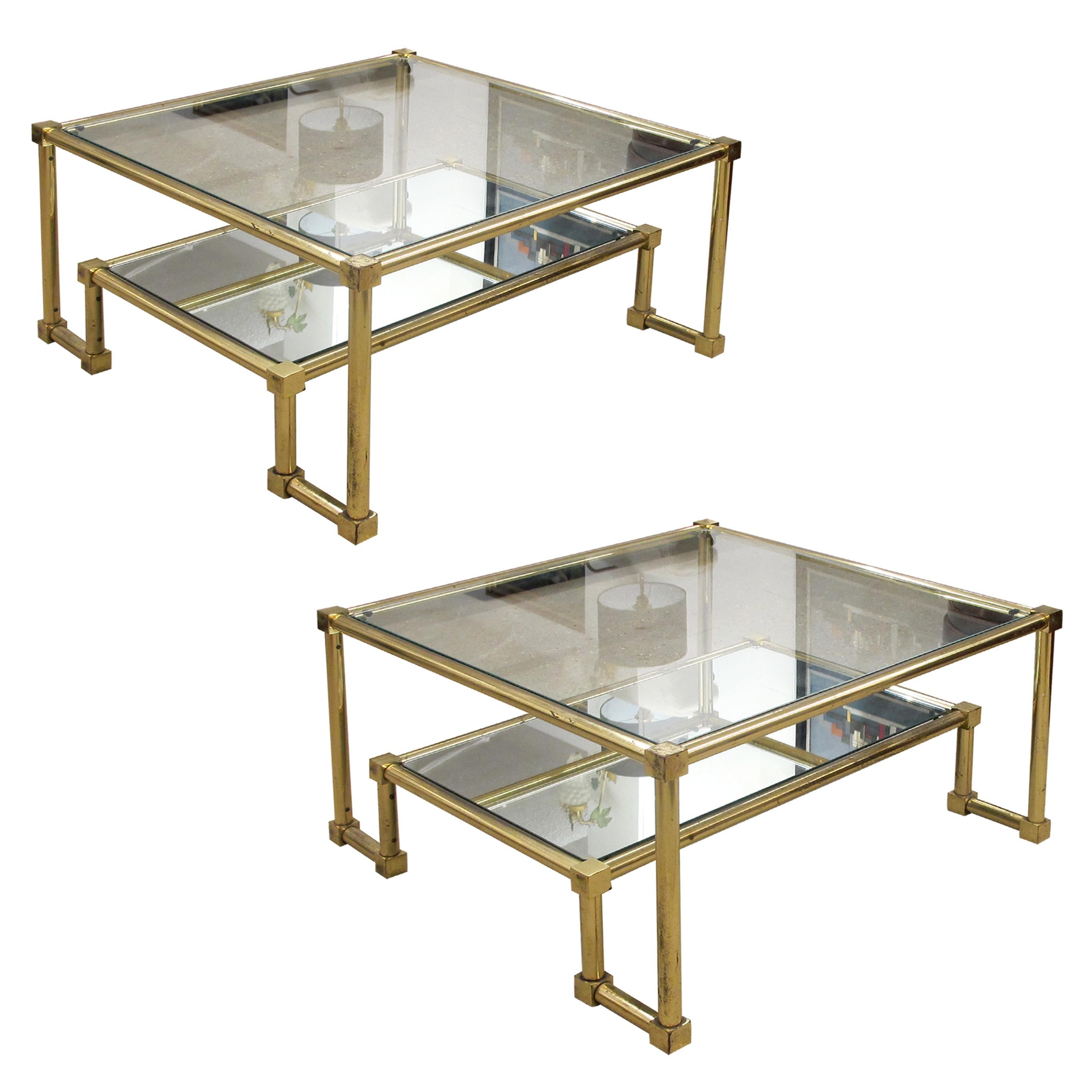 Pair of geometric Neoclassical two-tier brass coffee tables/side tables in the manner of Guy Lefevre, with clear glass tops and mirrored lower tiers. The tables are very versatile, they will look good to joined together to form a large coffee table.