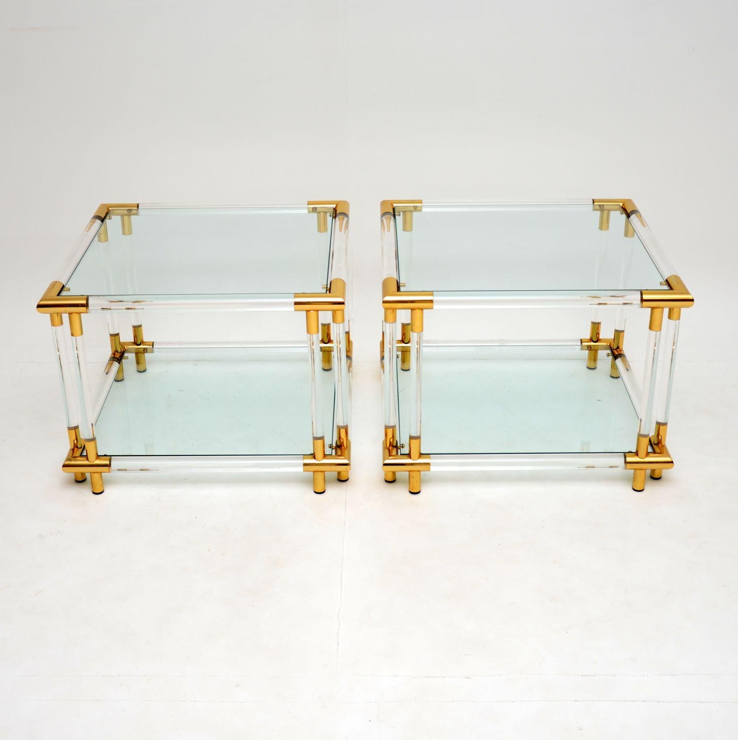 A superb pair of vintage glass top side tables, with clear acrylic frames accented with brass-plated aluminium. These were most likely made in France, they date from the 1970s.

The quality is fantastic, and these are in excellent condition